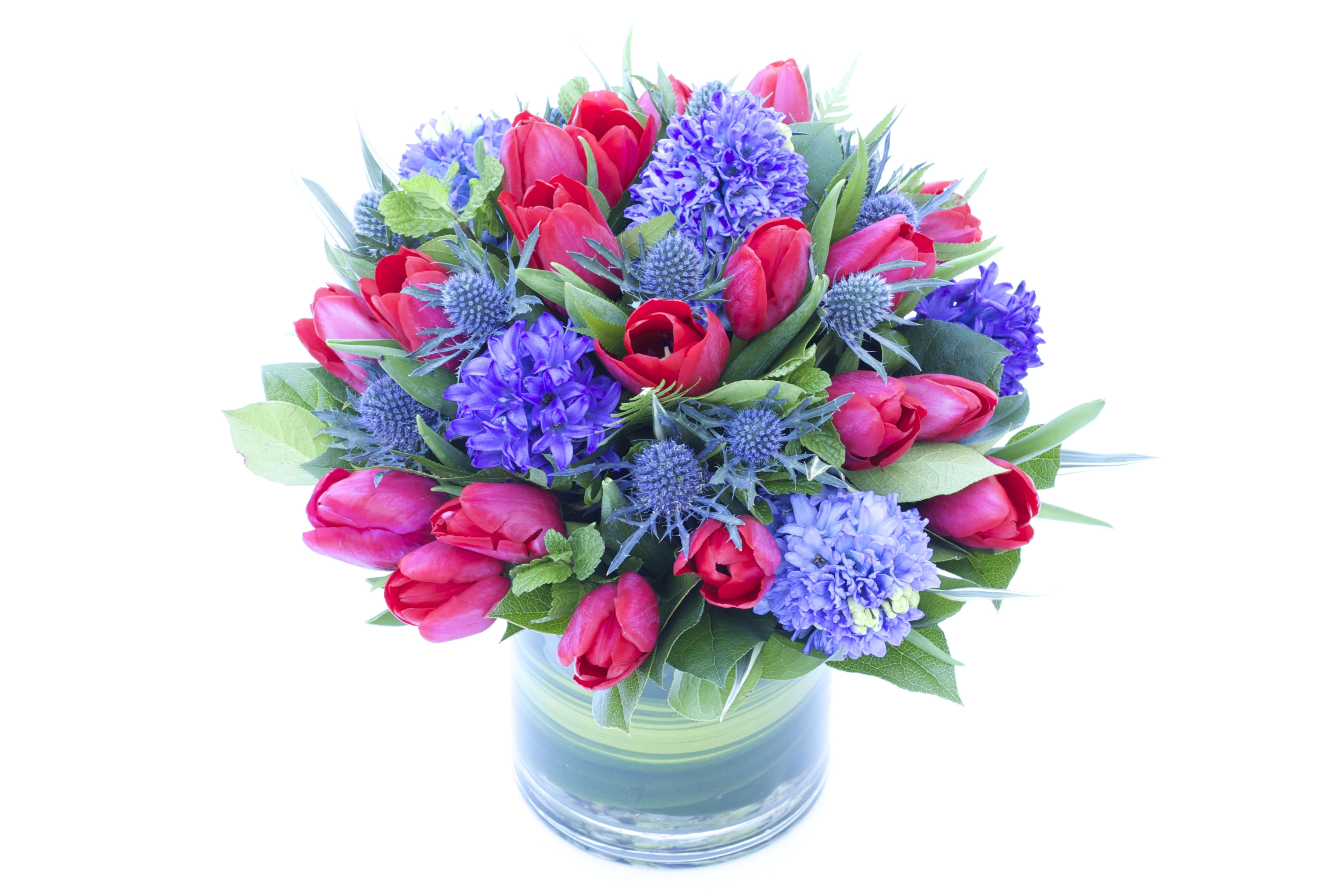 Bouquet of red tulips and purple flowers in a glass vase