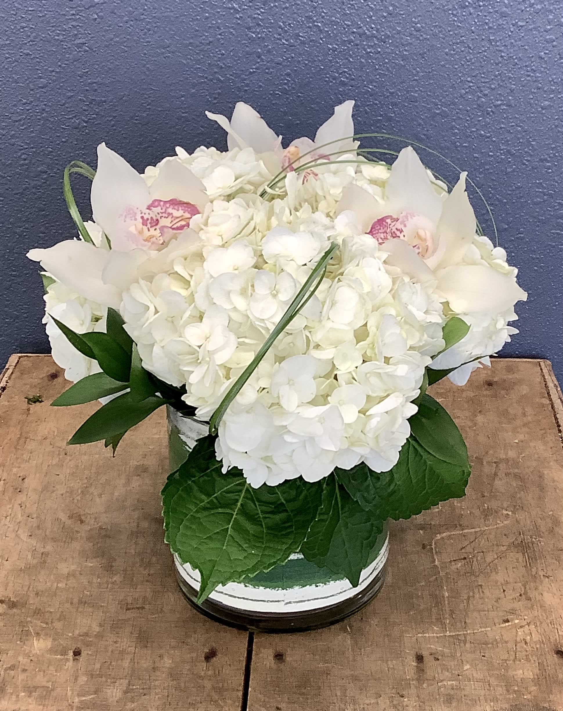 White hydrangea arrangement with white orchids in a low vase