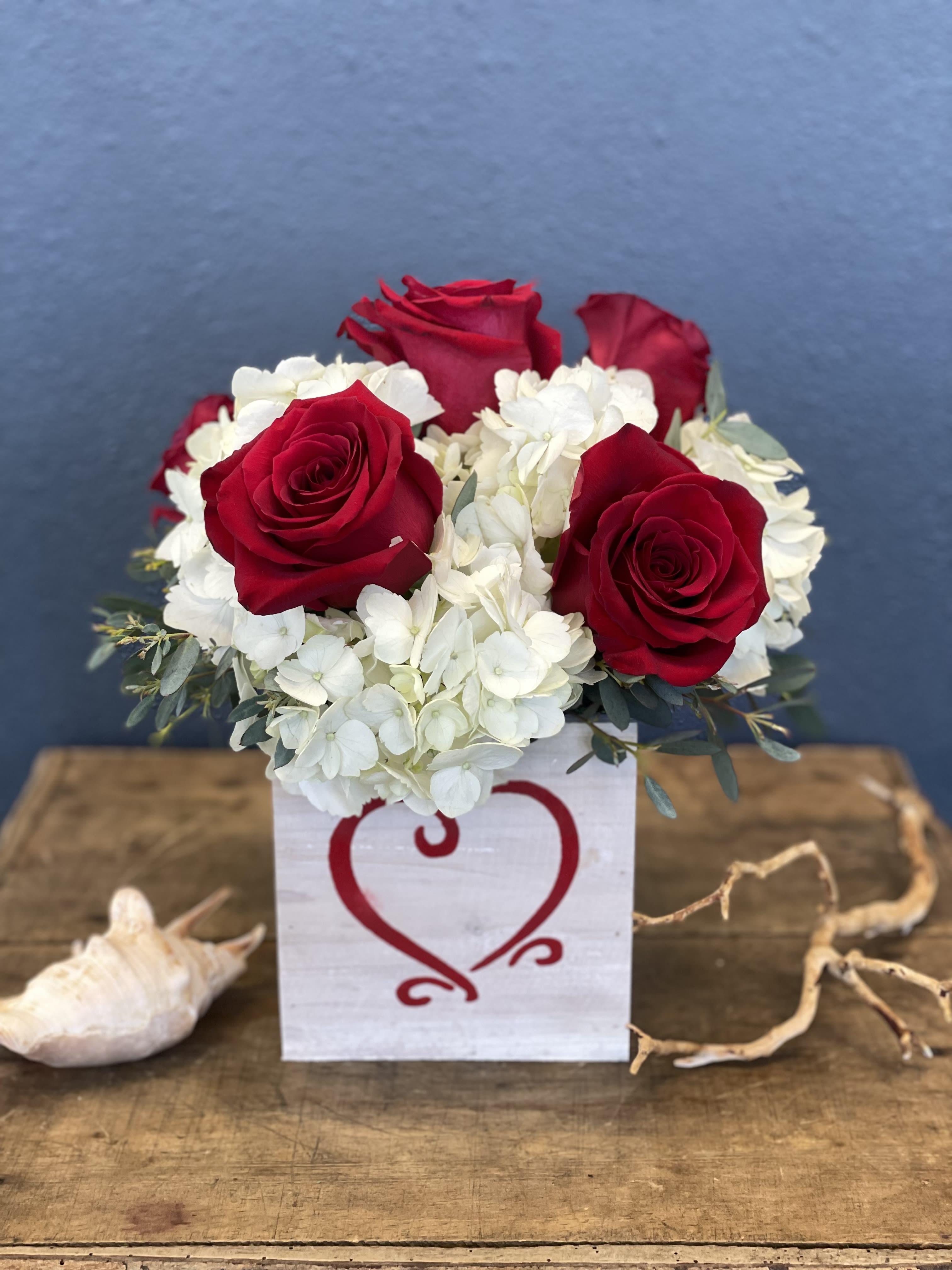 Red roses and white hydrangeas in a white box with a heart design