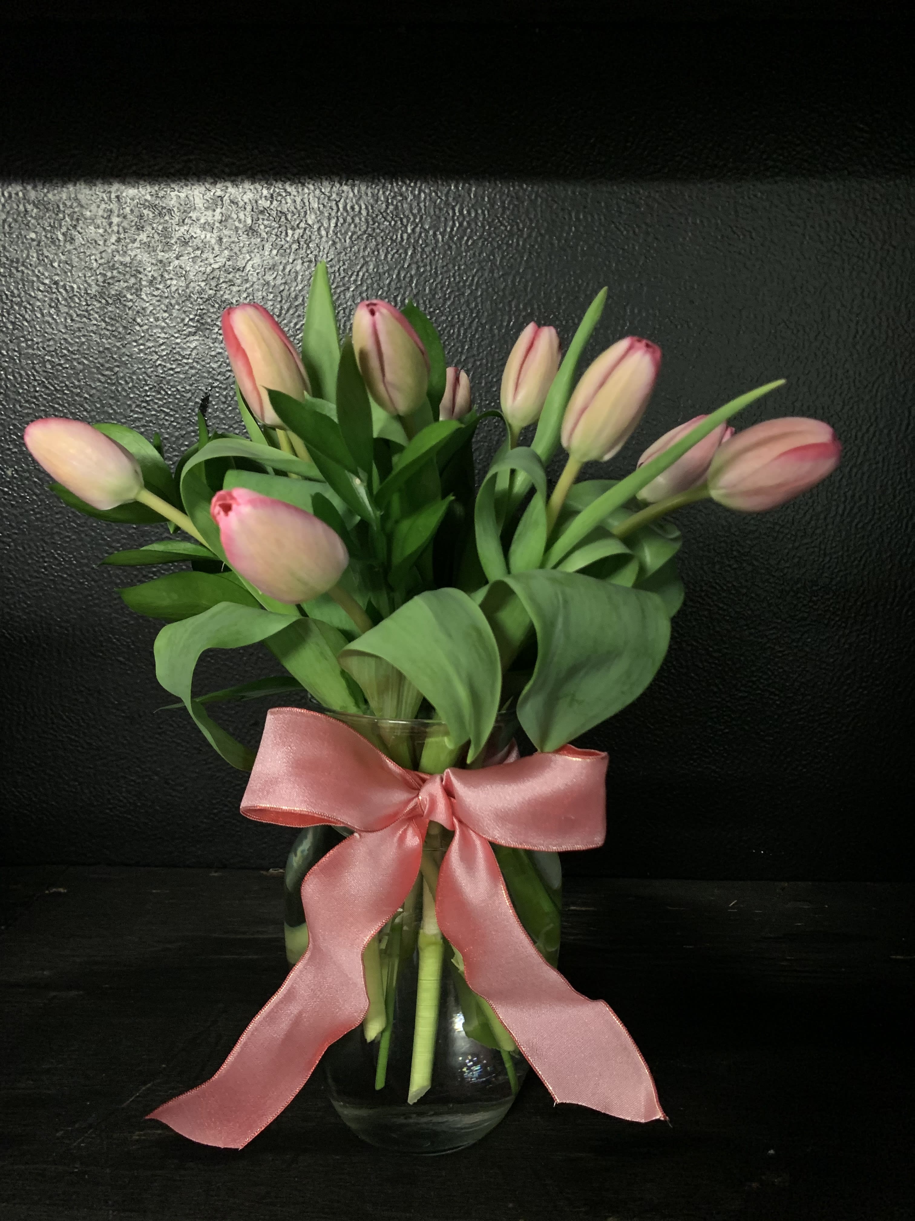 Pink tulips in a glass vase with a pink ribbon bow