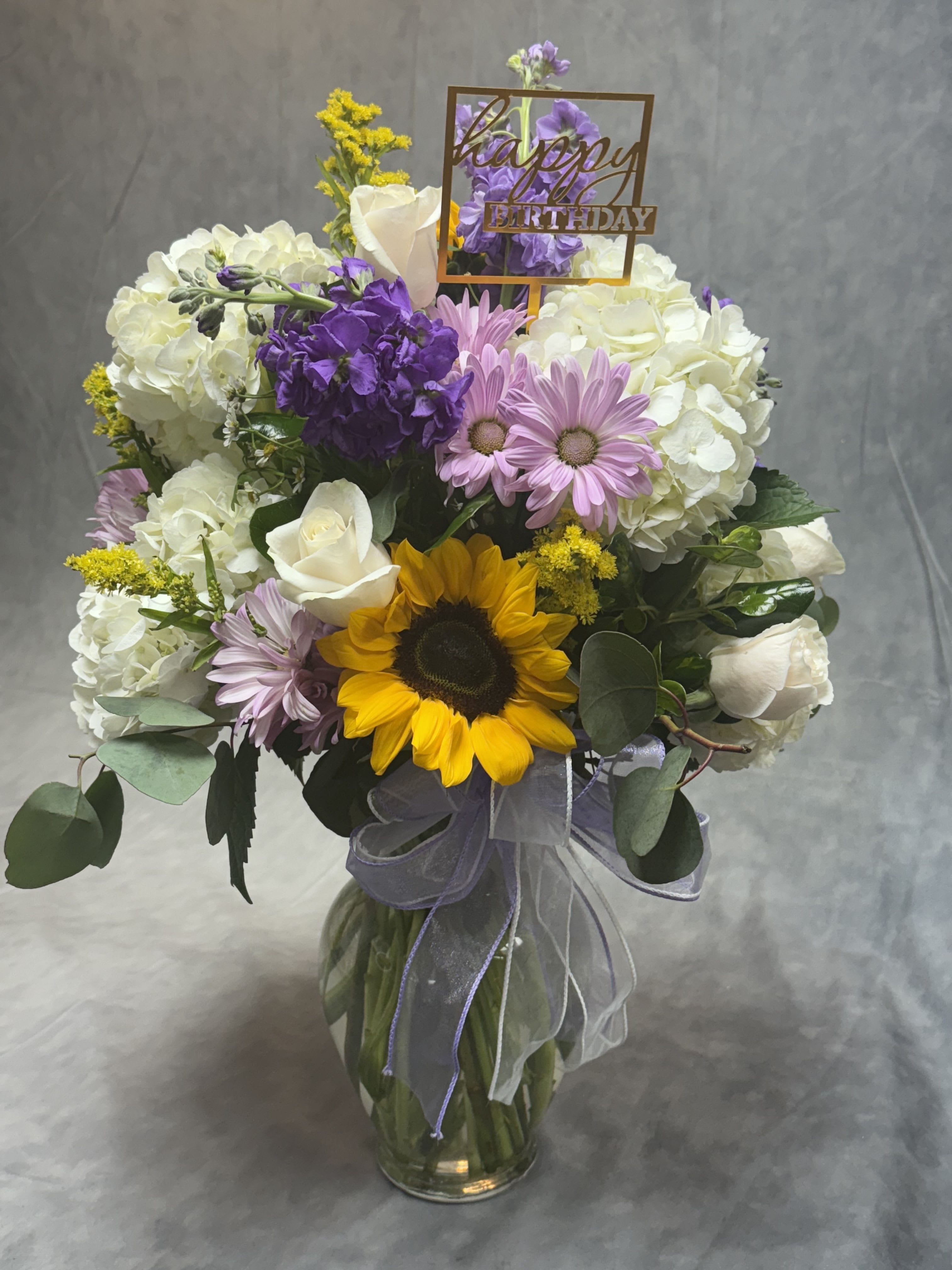 Mixed bouquet in a glass vase with a happy birthday sign