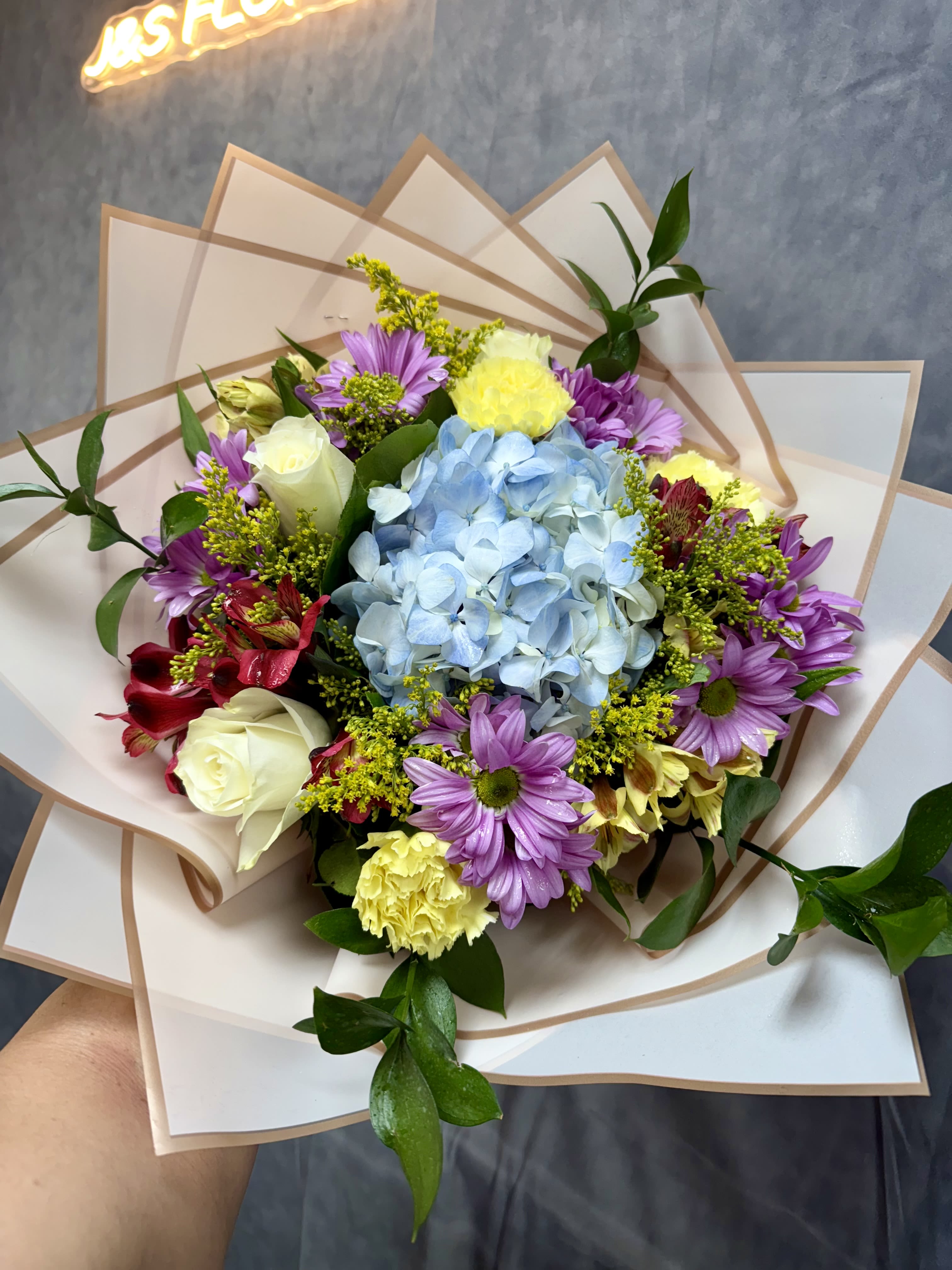 Bouquet with blue hydrangea, purple daisies, and white roses in paper wrap