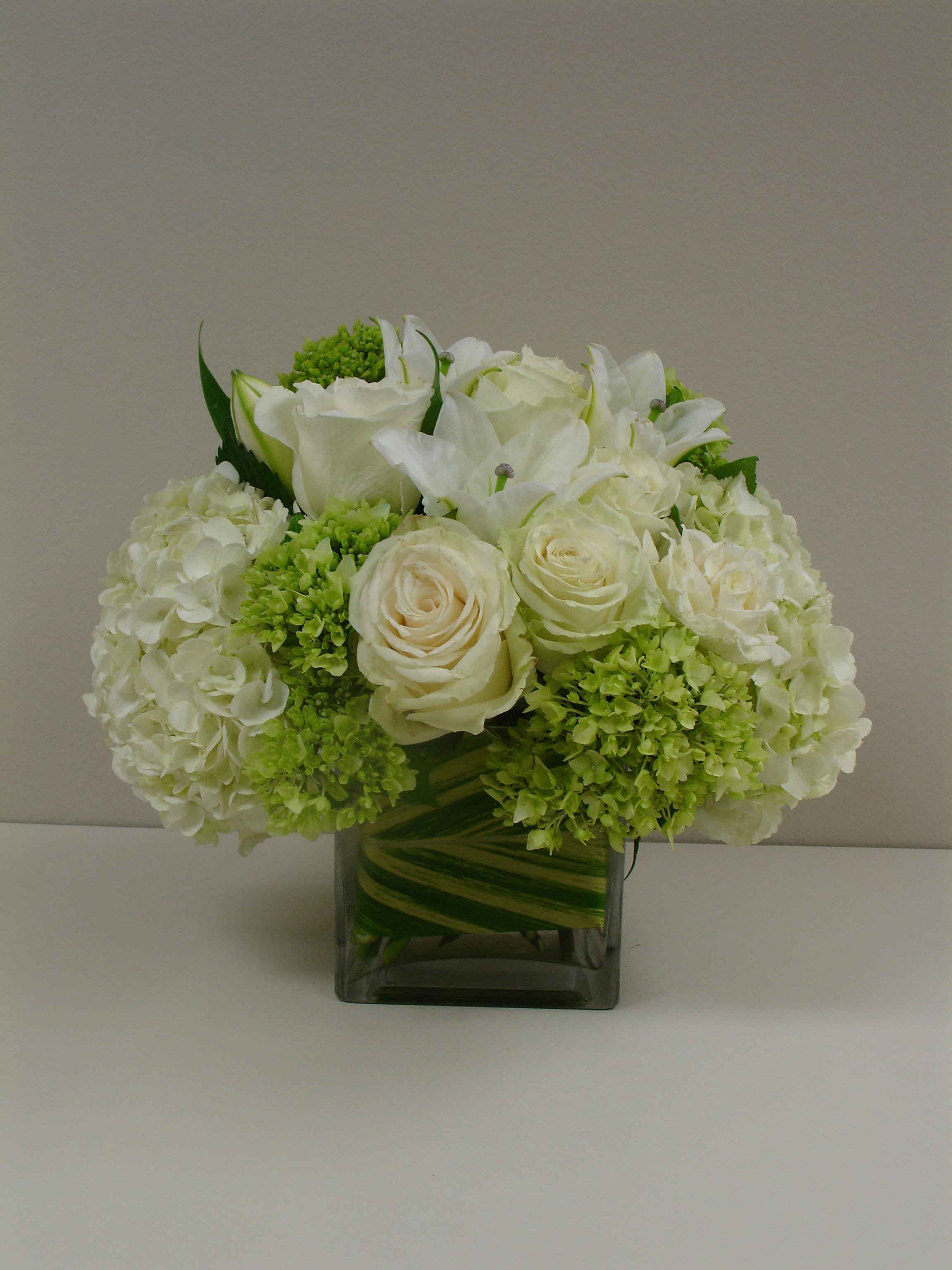 White roses and hydrangeas arranged in a square glass vase