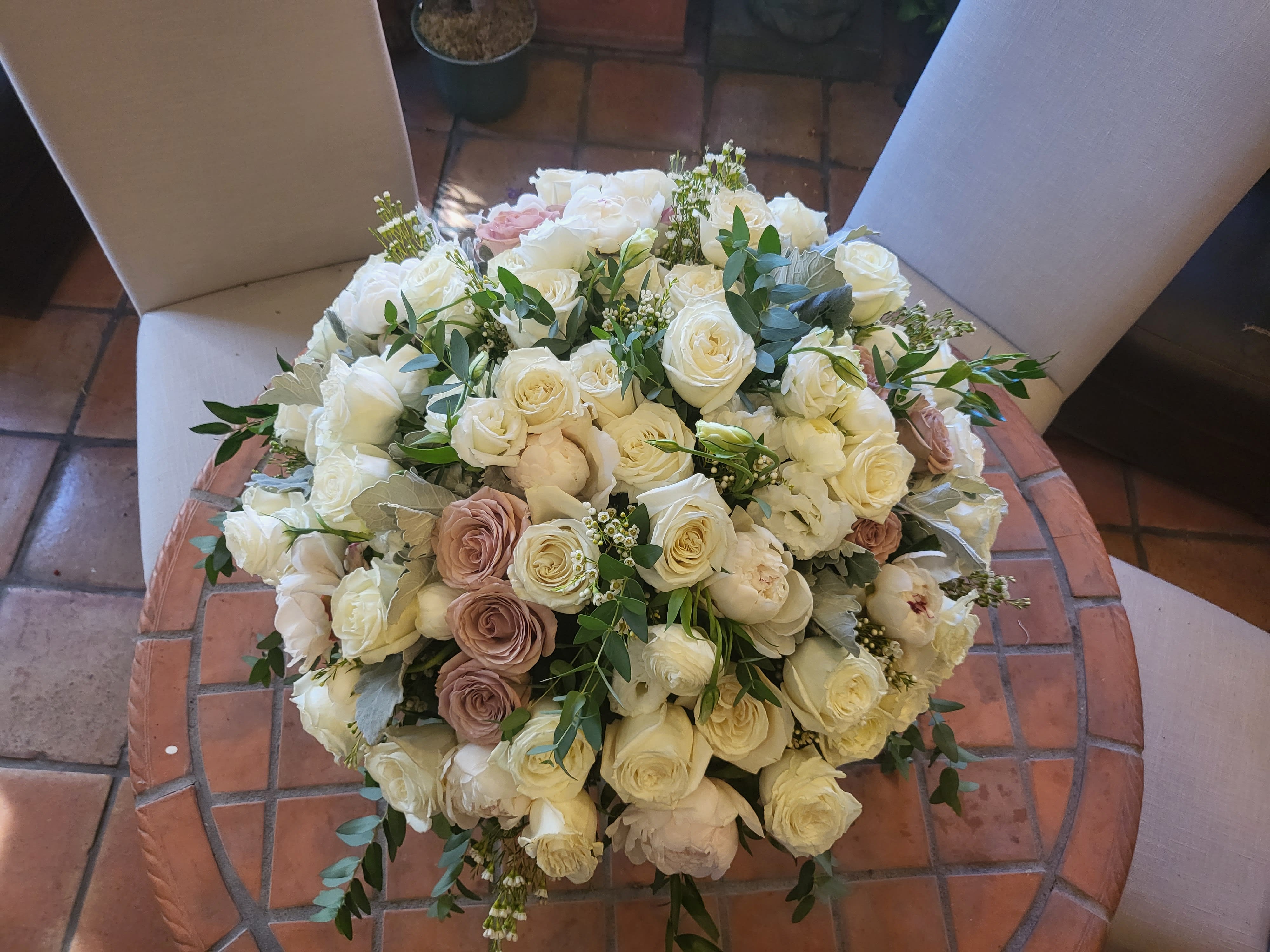 Large bouquet of white and blush roses with greenery on a chair