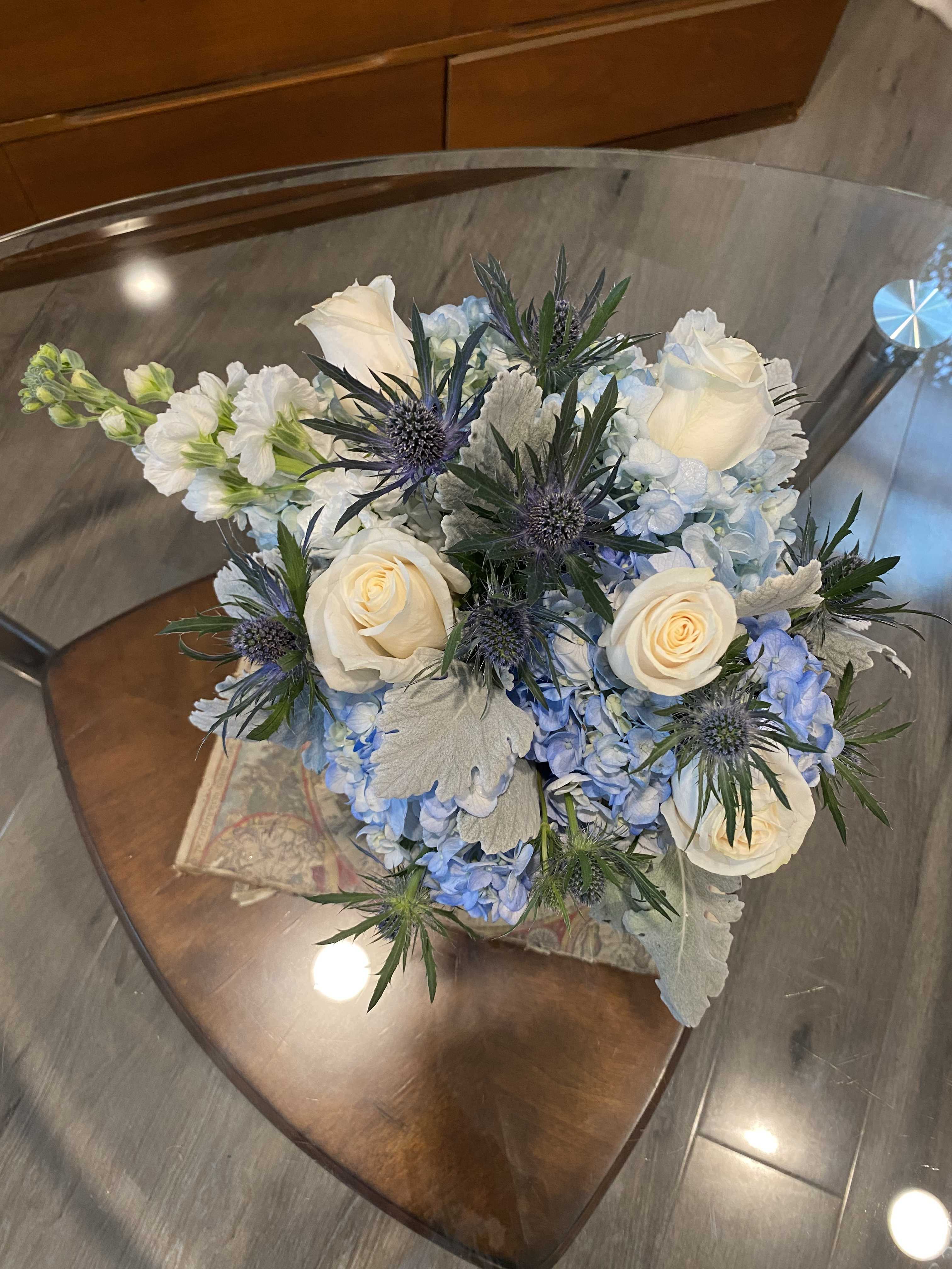 Bouquet of white roses and blue hydrangeas with spiky thistle flowers