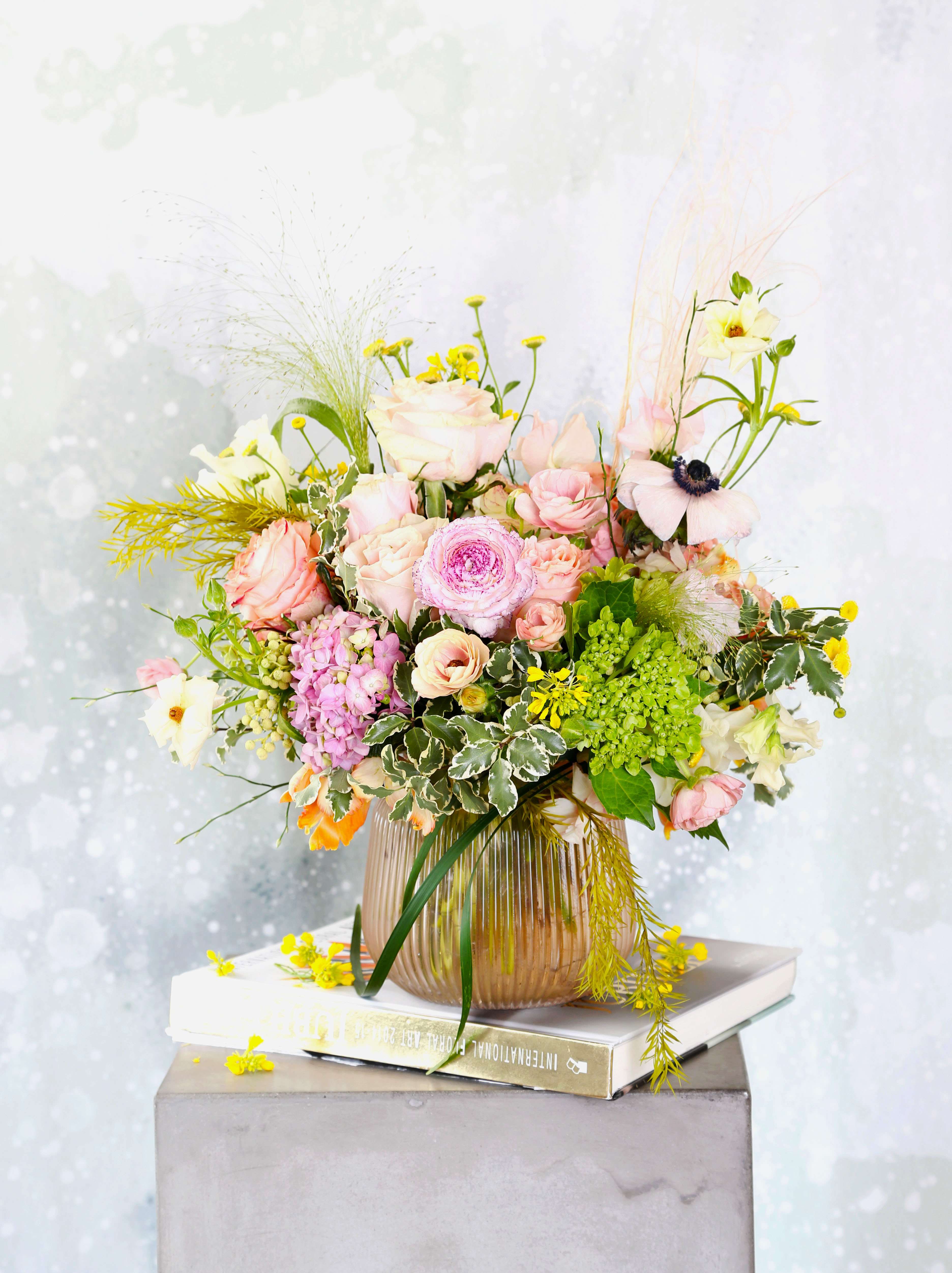 Peach Fuzz -  This arrangement creates in the elegance rosy glass vase. A rounder shape with lots of spring summer bloom like Pink garden rose, Japanese sweet pea, ranunculus, lisianthus and much more. A compact more tradition arrangement with peach to blush to yellow color way. This arrangement will deliver with gift box as pic shown