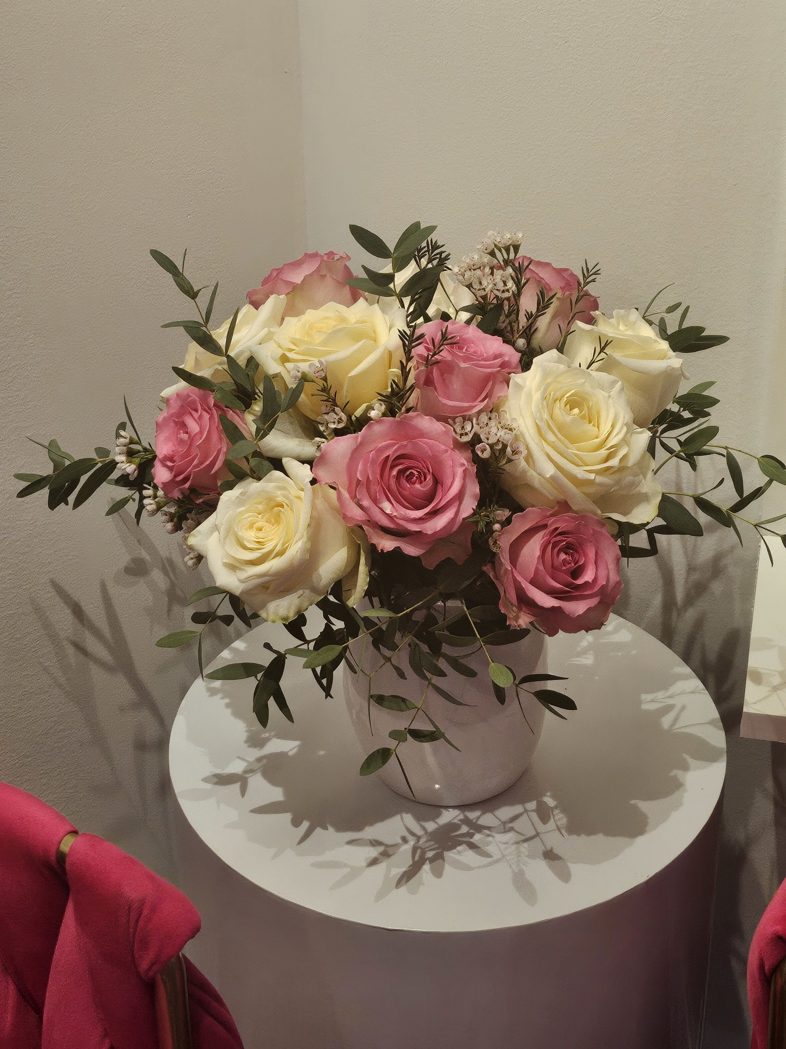 Pink and cream roses arranged in a white vase