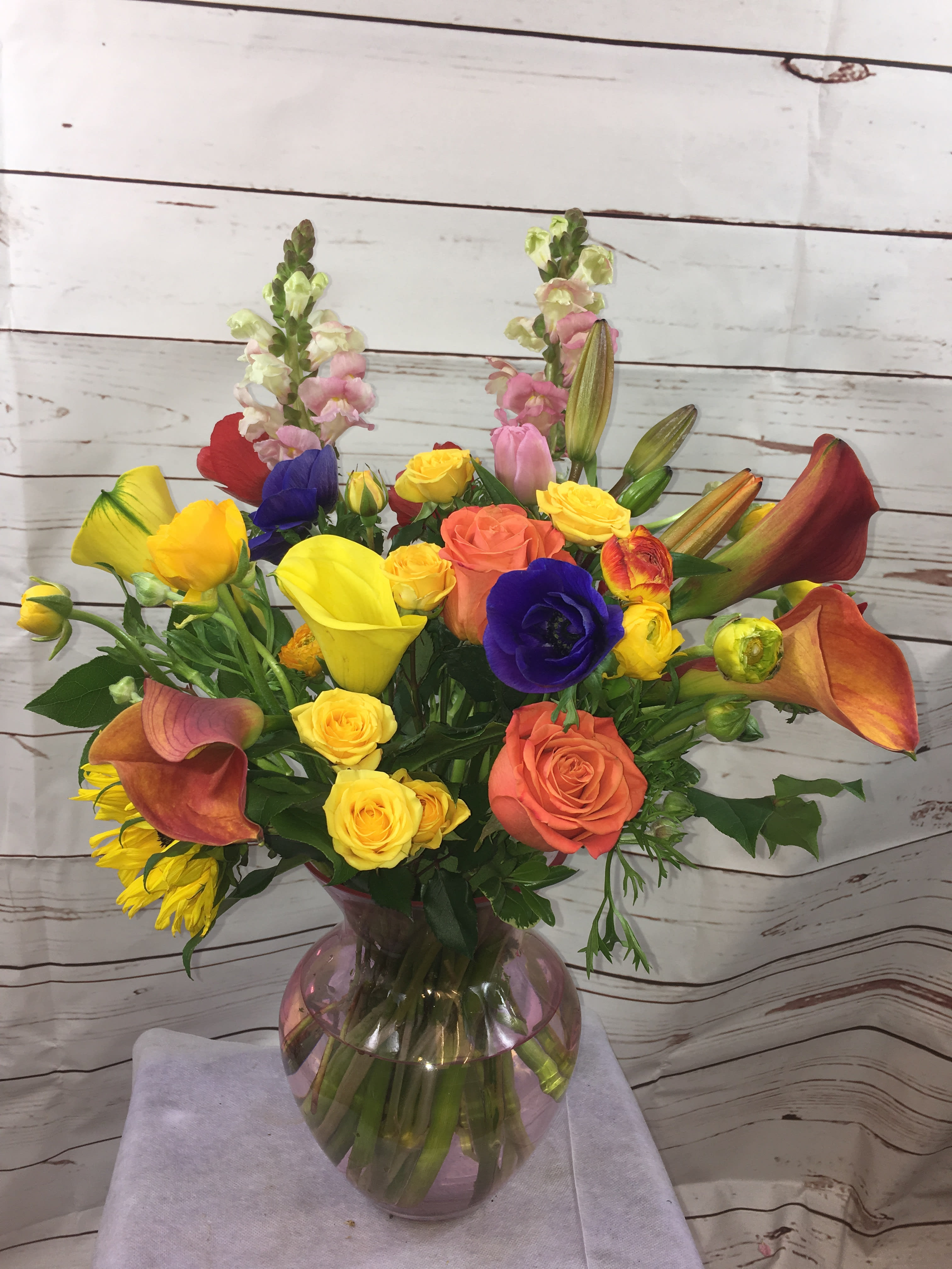 Mixed bouquet with roses, calla lilies, and snapdragons in a glass vase