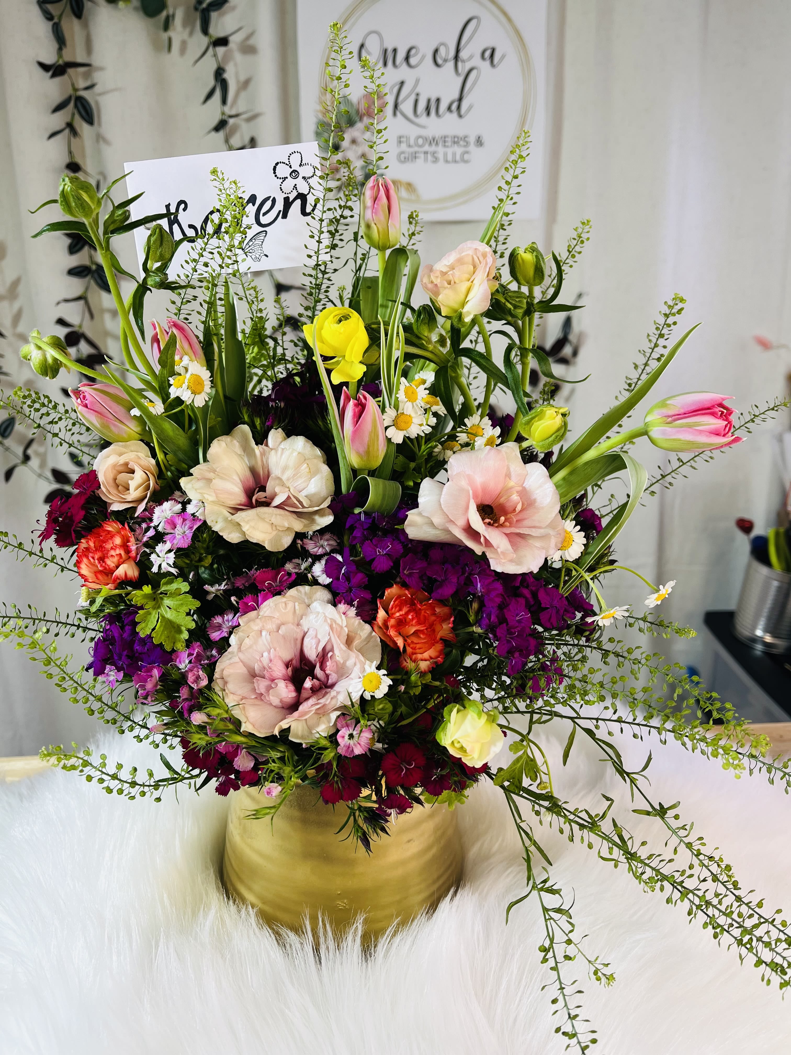 Mixed bouquet of tulips, roses, and small daisies in a gold vase