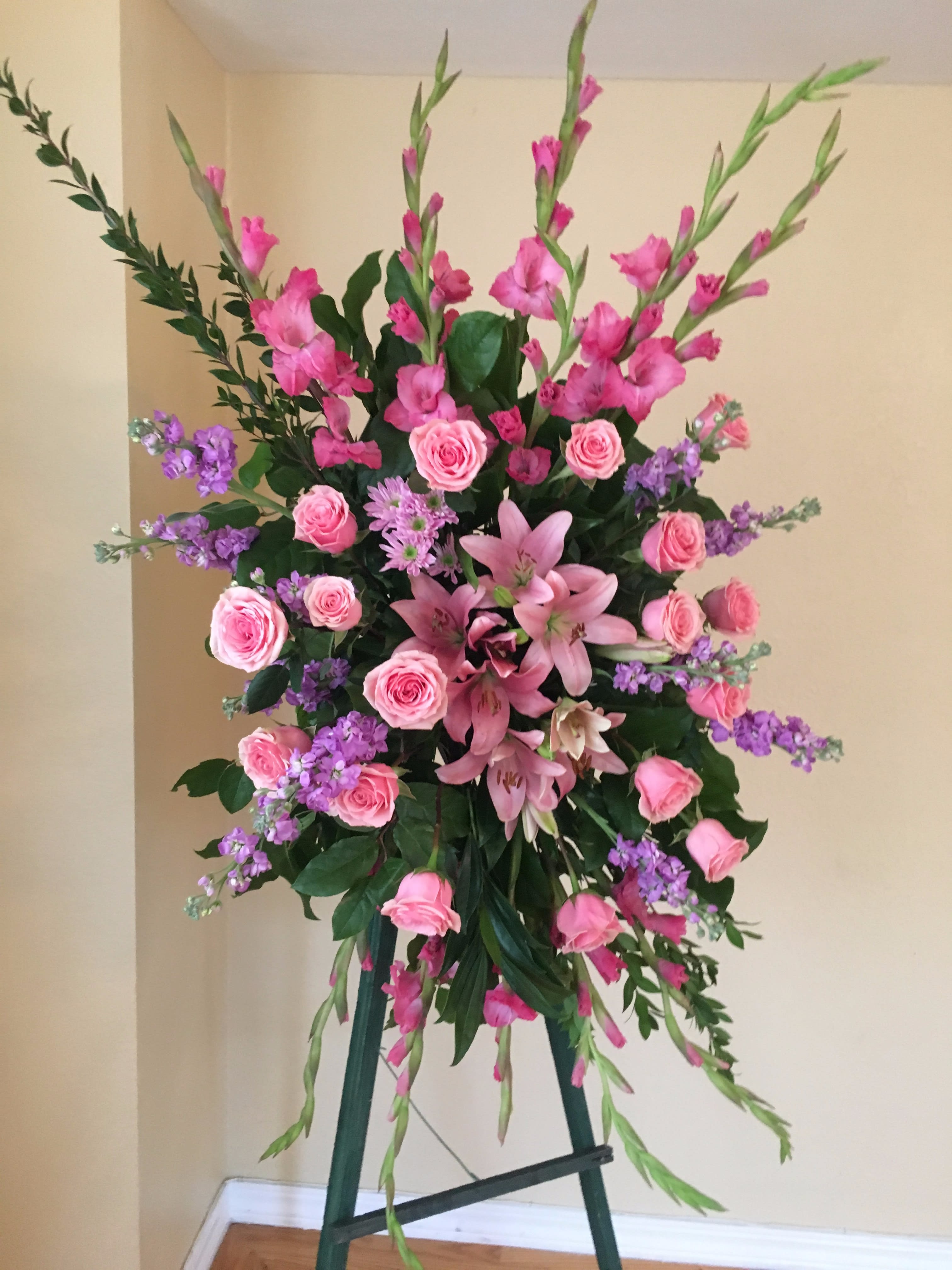 Standing floral spray with pink roses, lilies, and purple accents
