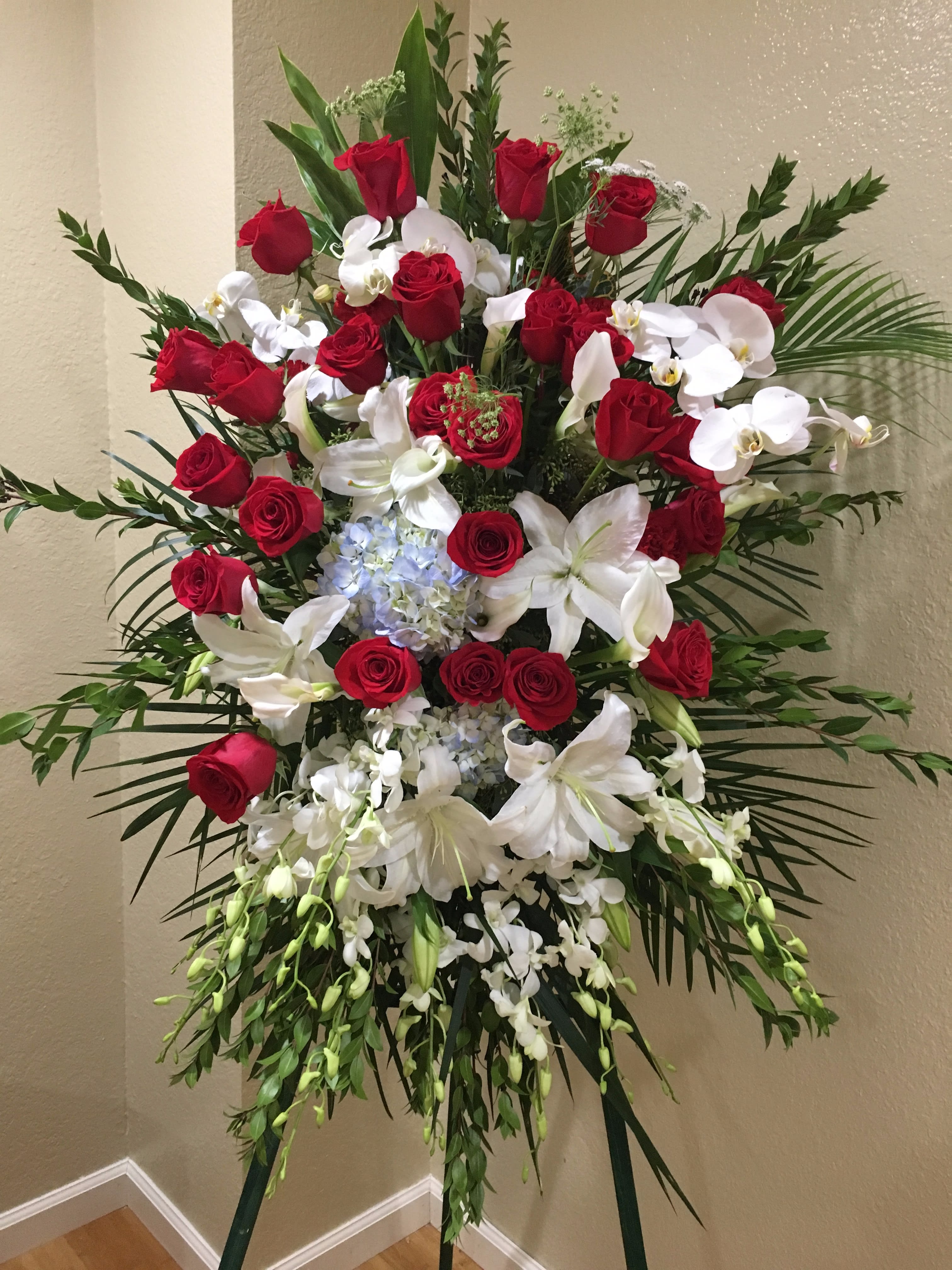 Standing floral spray with red roses, white lilies, and orchids