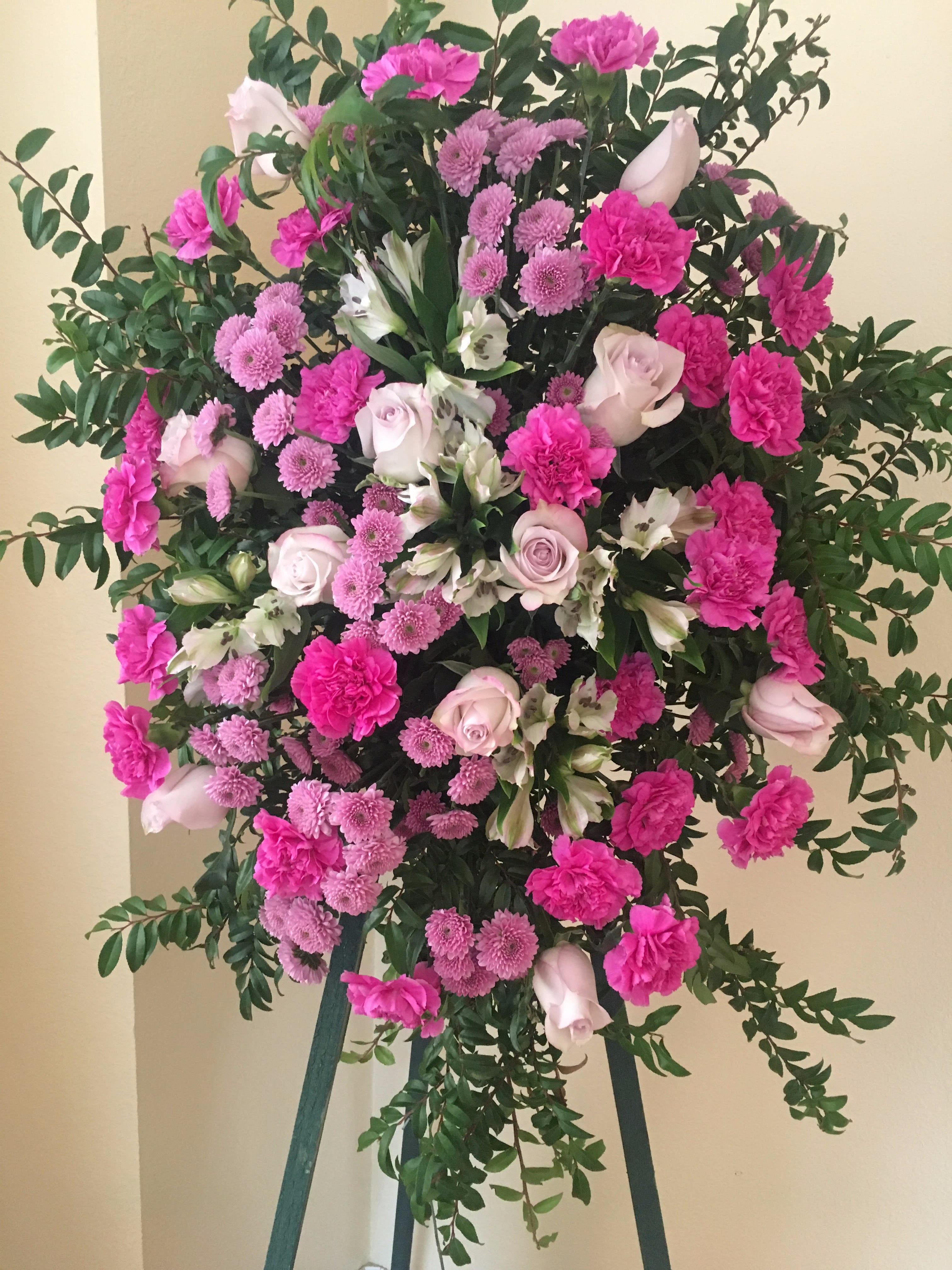 Standing floral spray with pink and white flowers on a tripod easel