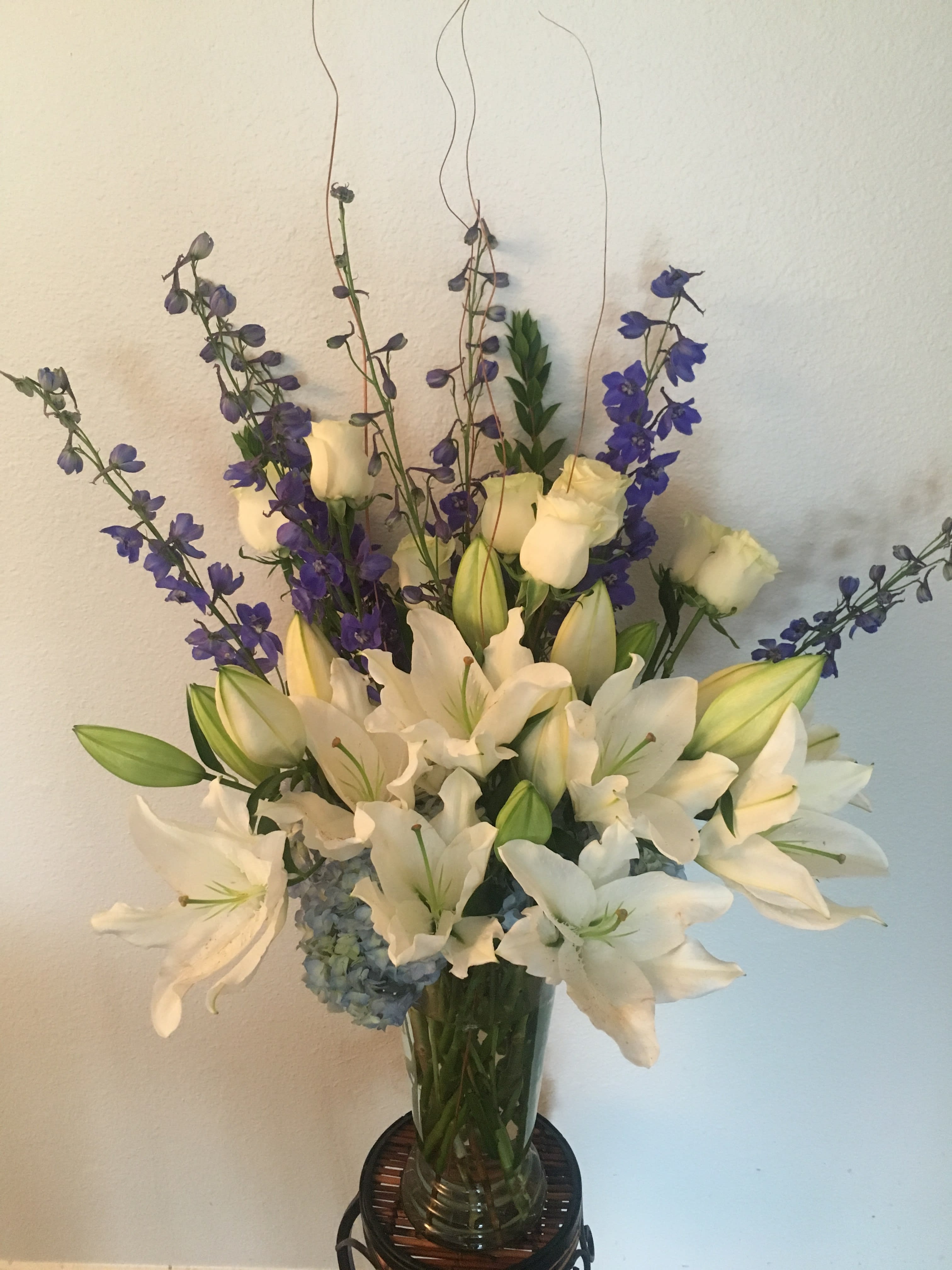 White lilies and purple delphinium in a glass vase