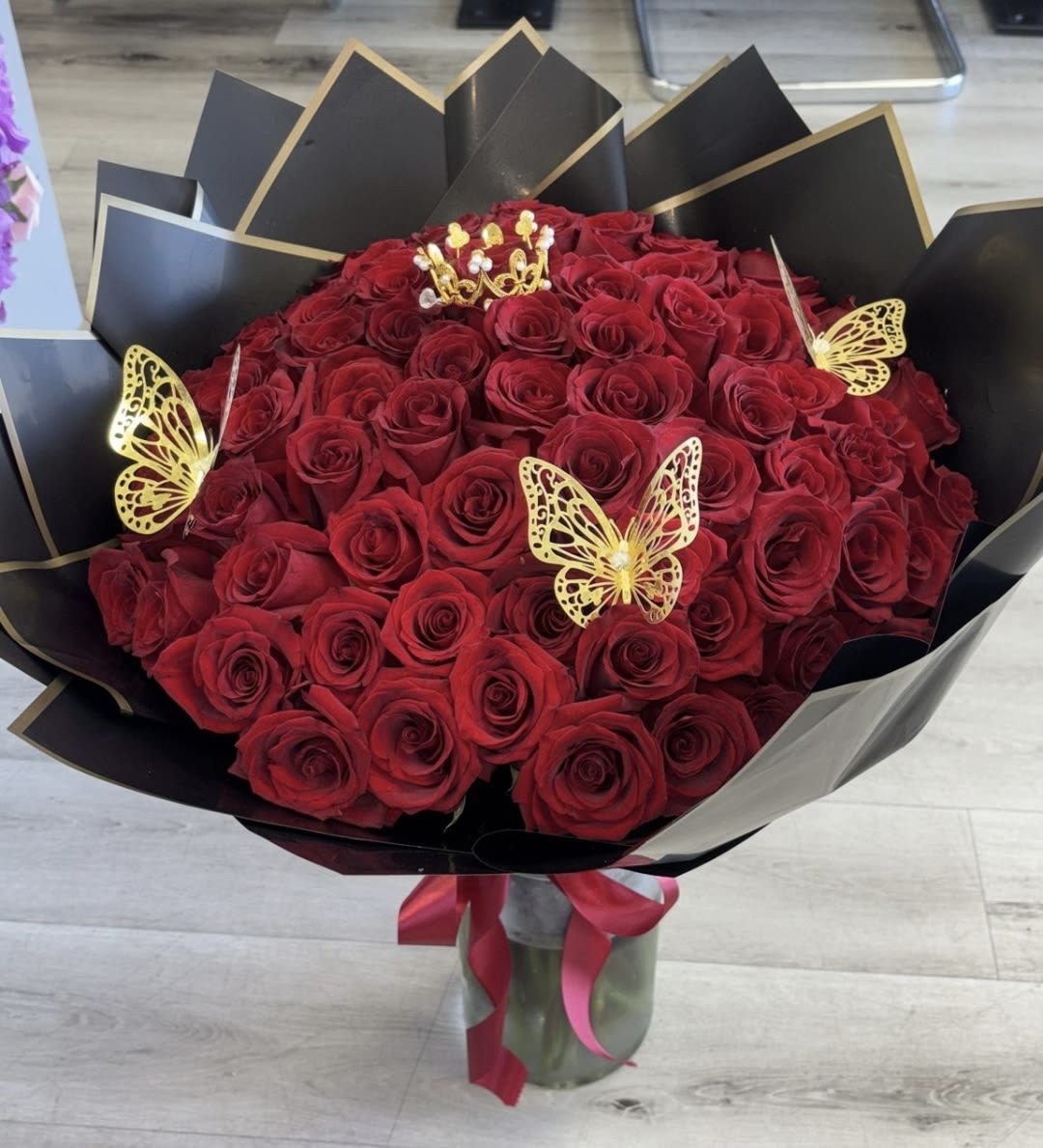 Bouquet of red roses with gold butterfly accents in black wrap