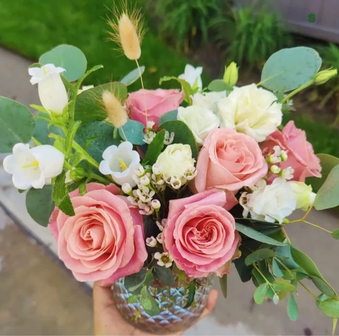 Pink and white rose bouquet in a glass vase with eucalyptus and small white blooms