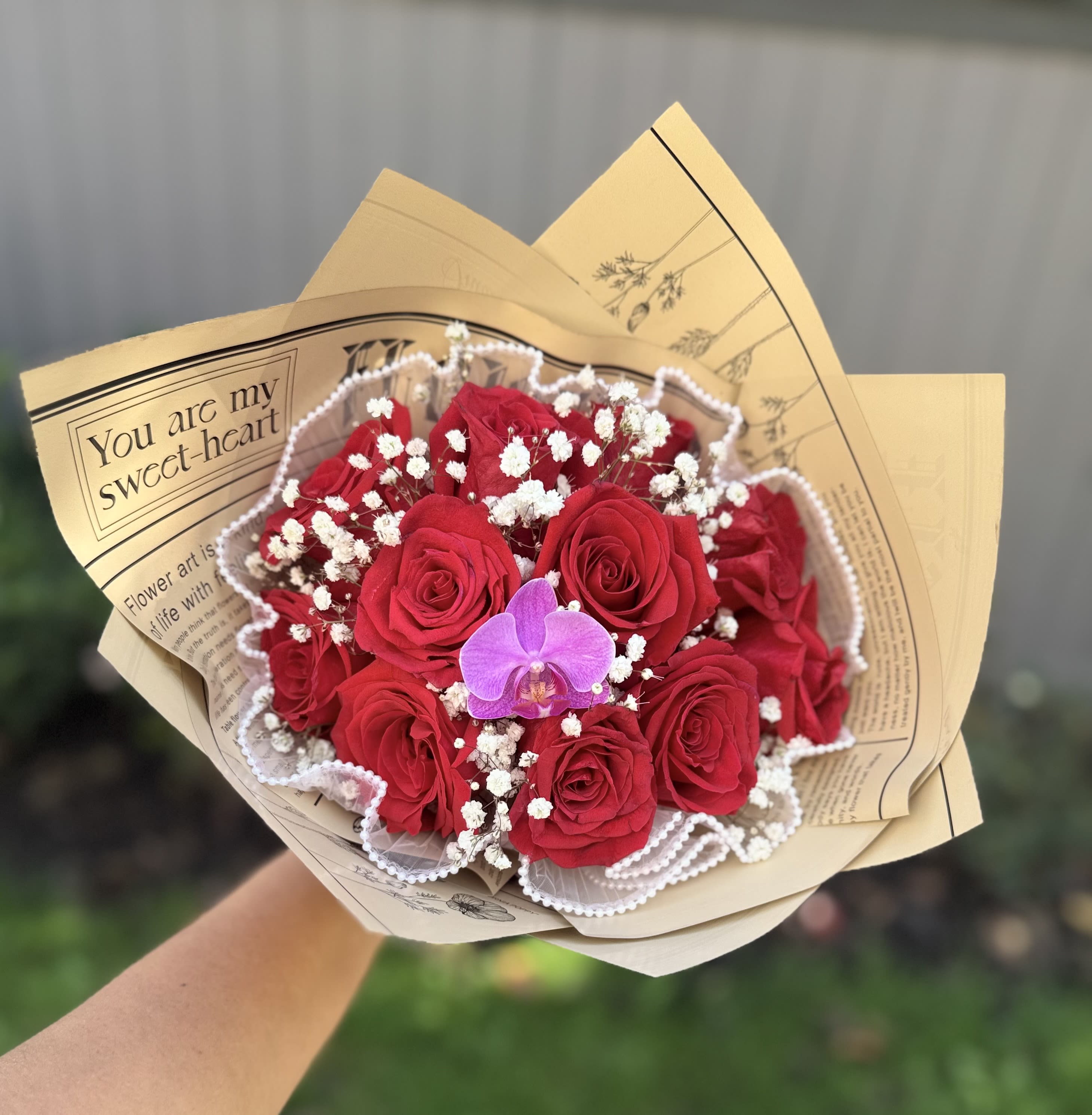 Bouquet of red roses with white baby's breath and a purple orchid