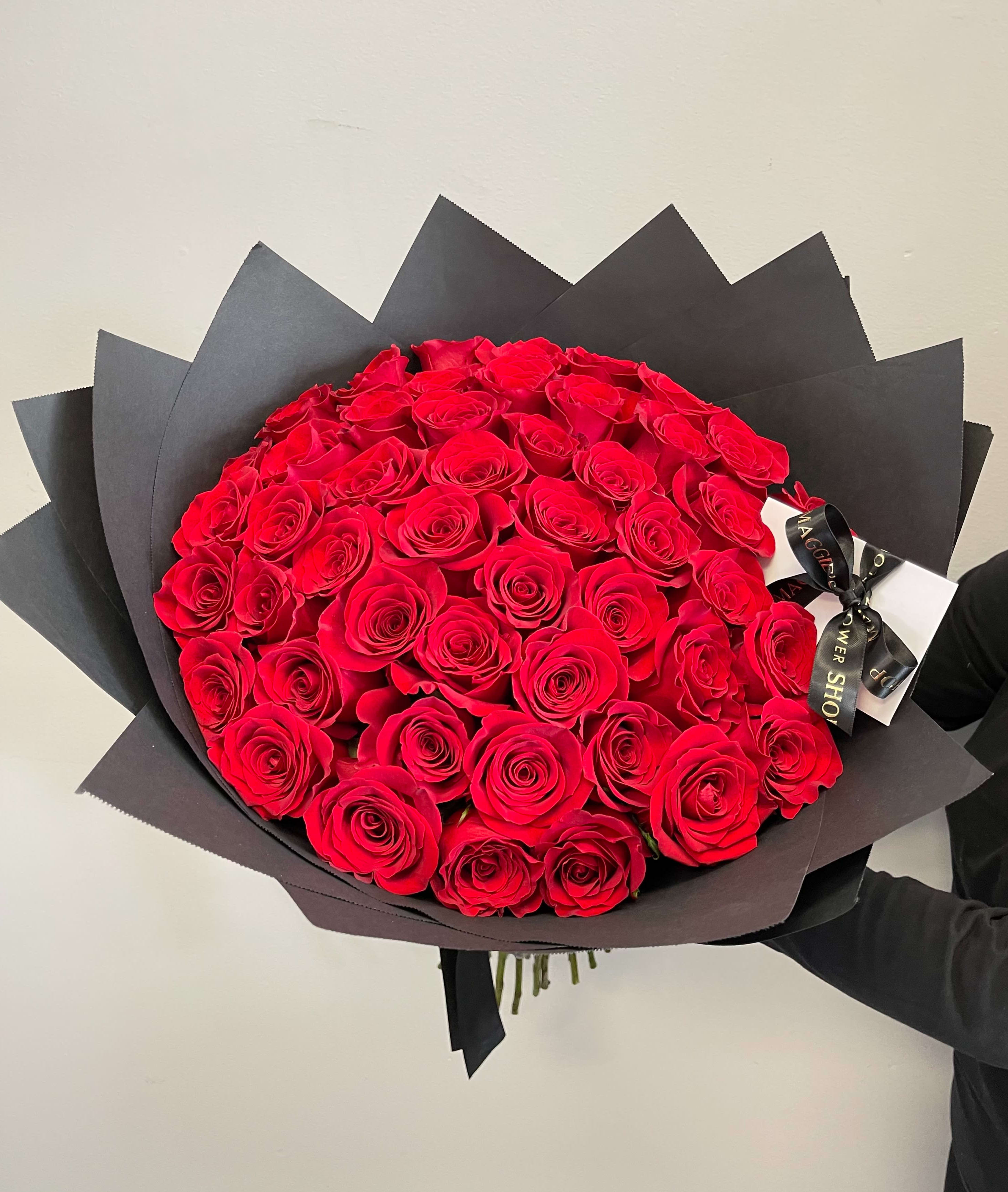 Large bouquet of red roses wrapped in black paper with a ribbon