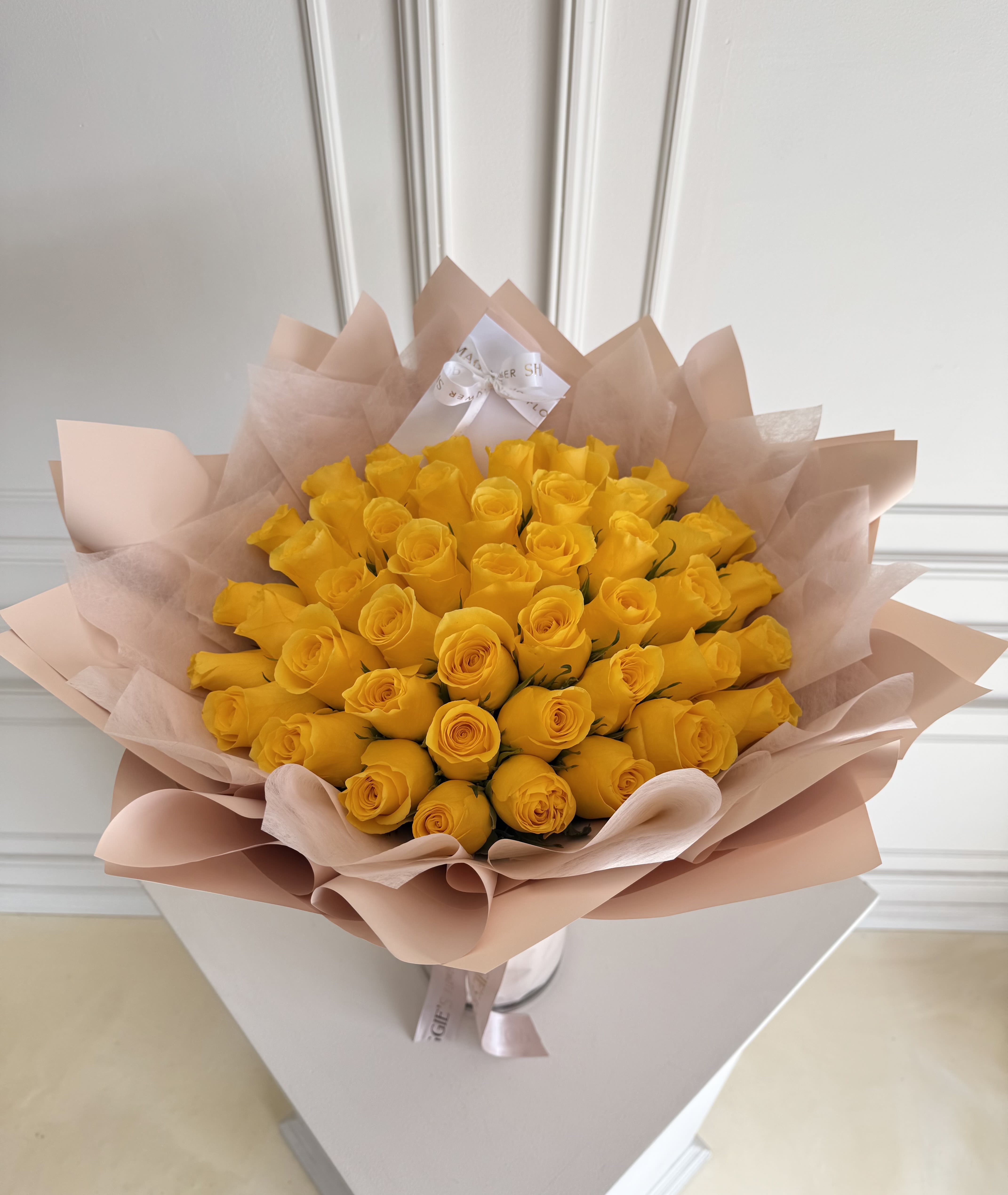 Bouquet of yellow roses wrapped in pale pink paper