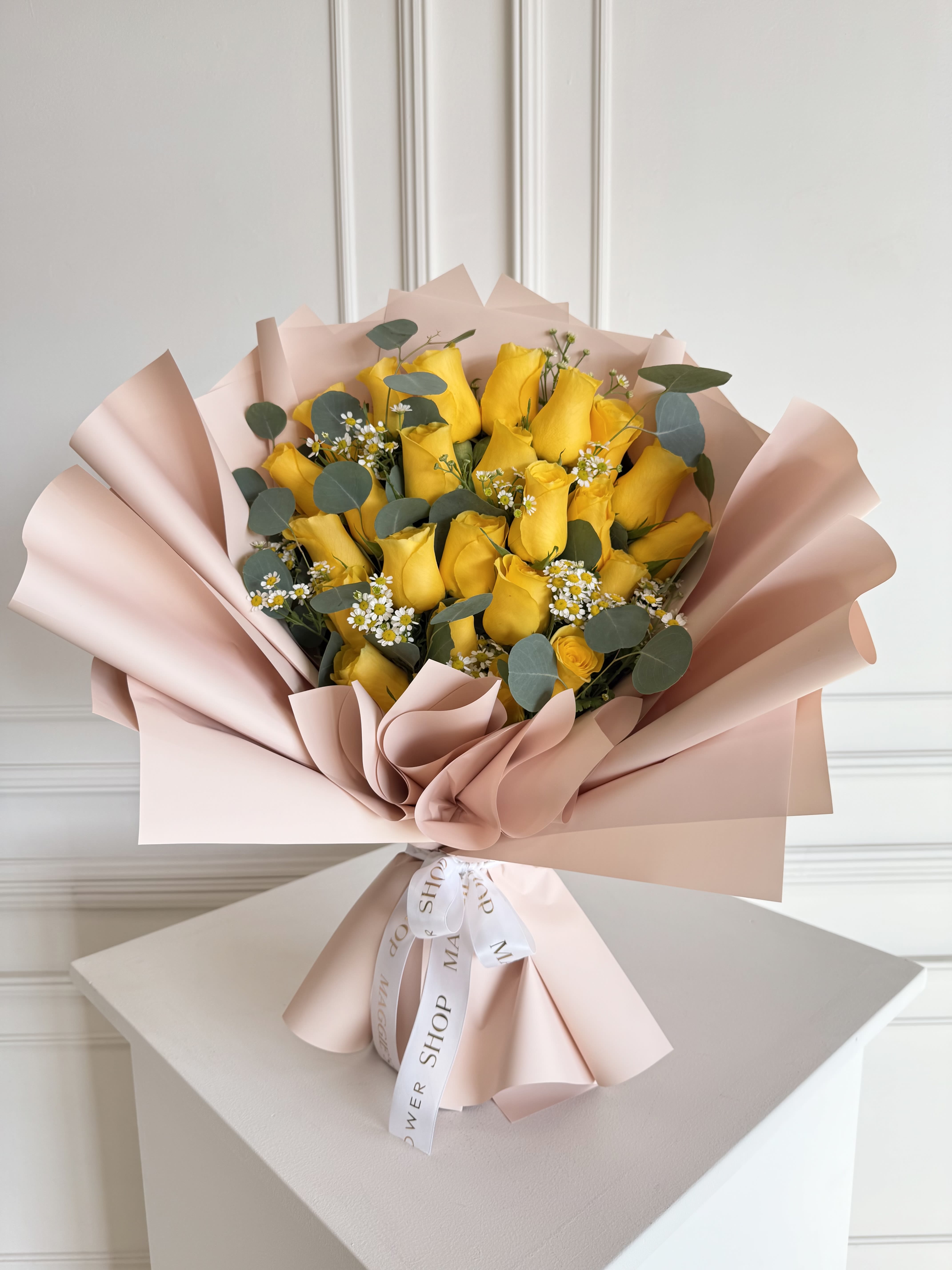 Bouquet of yellow roses wrapped in blush pink paper
