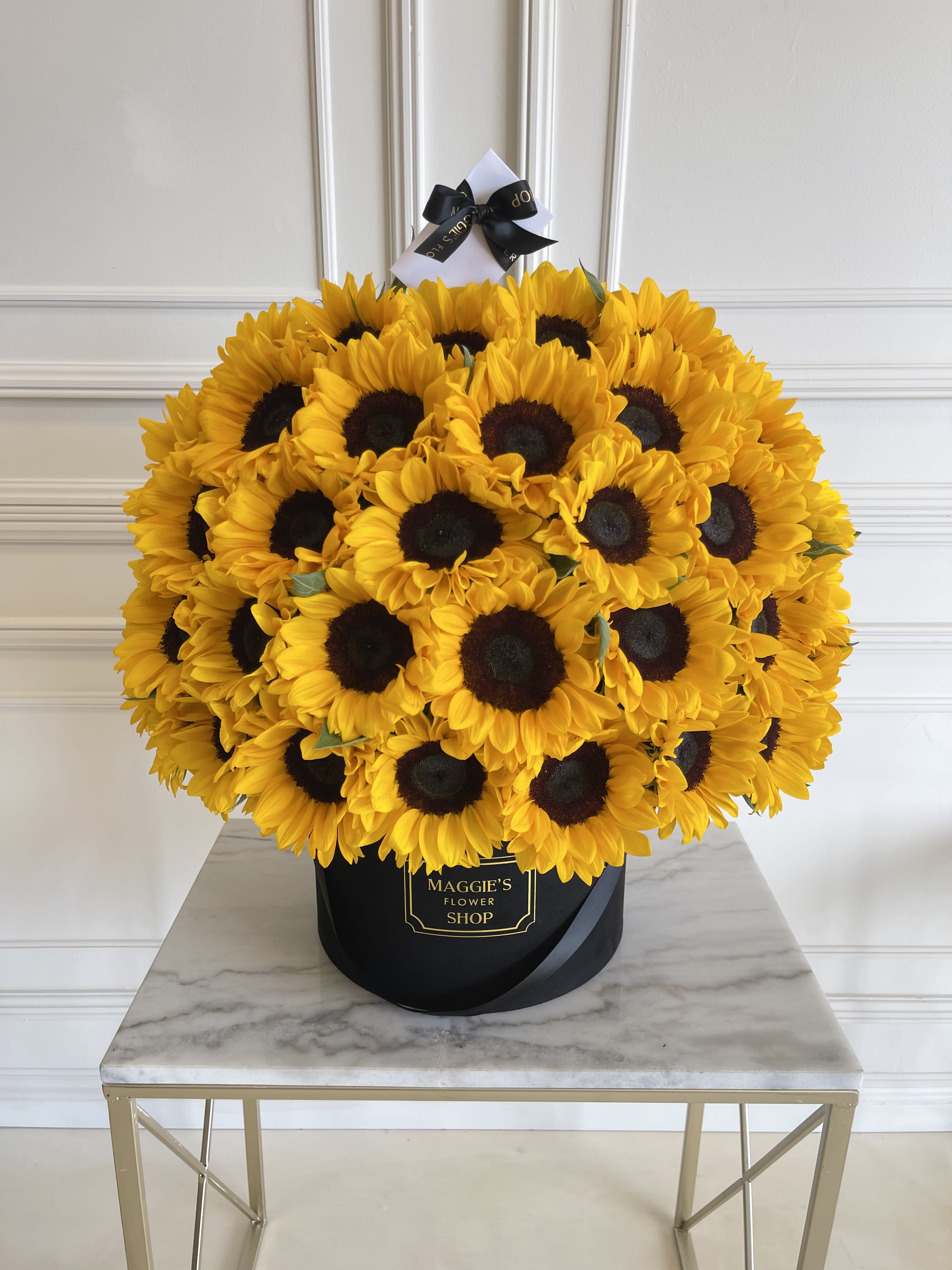 Large bouquet of yellow sunflowers in a black hatbox with a ribbon