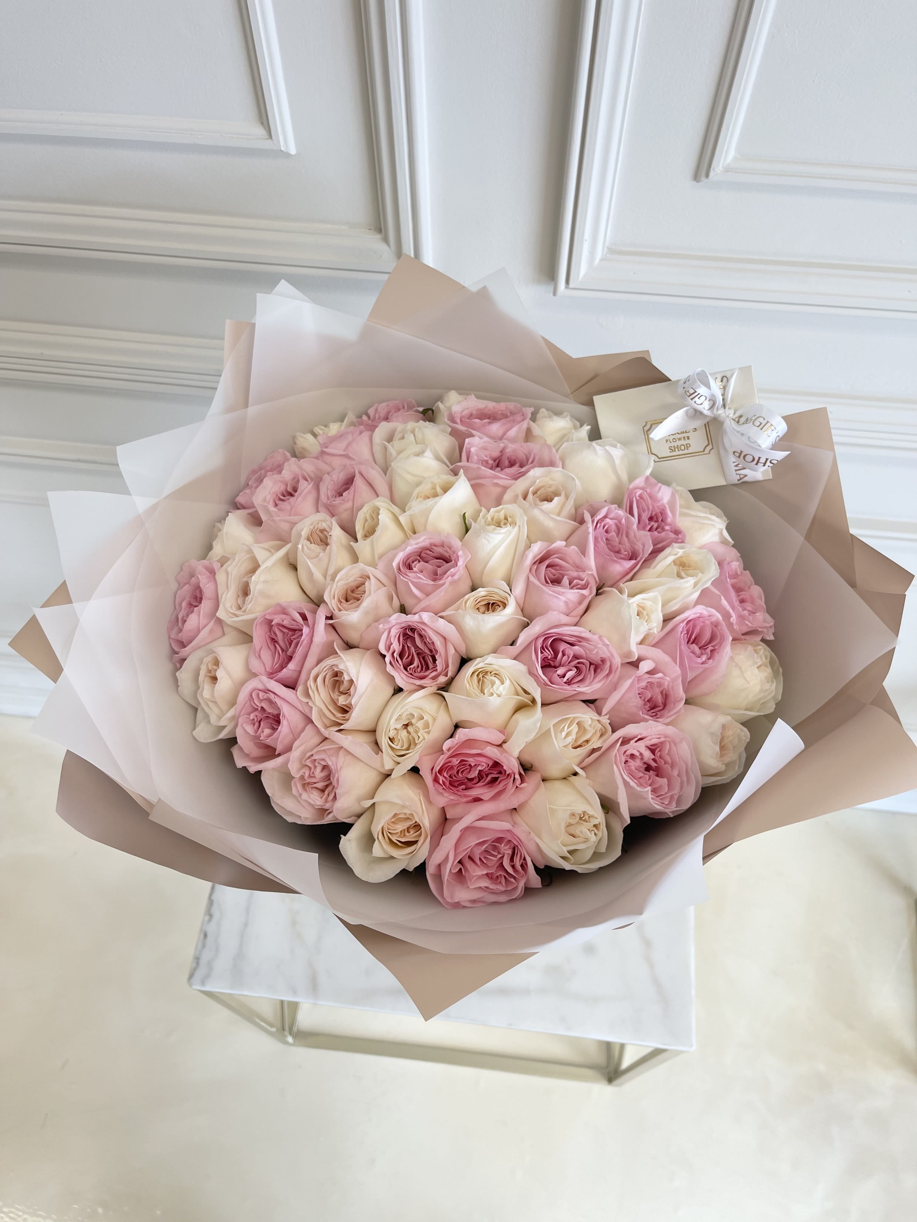 Large bouquet of pink and cream roses wrapped in blush paper