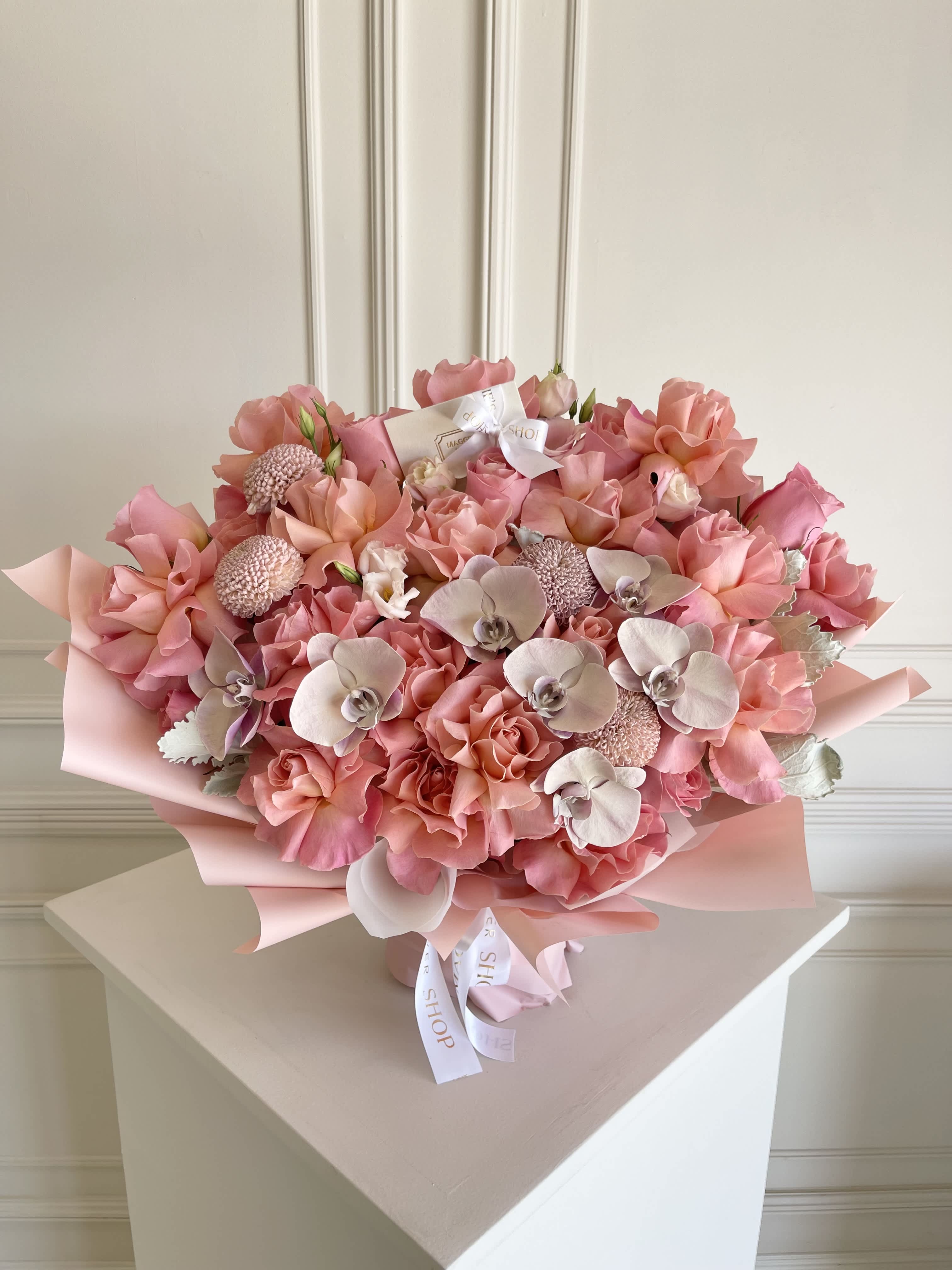 Large pink bouquet with roses and orchids wrapped in pastel paper