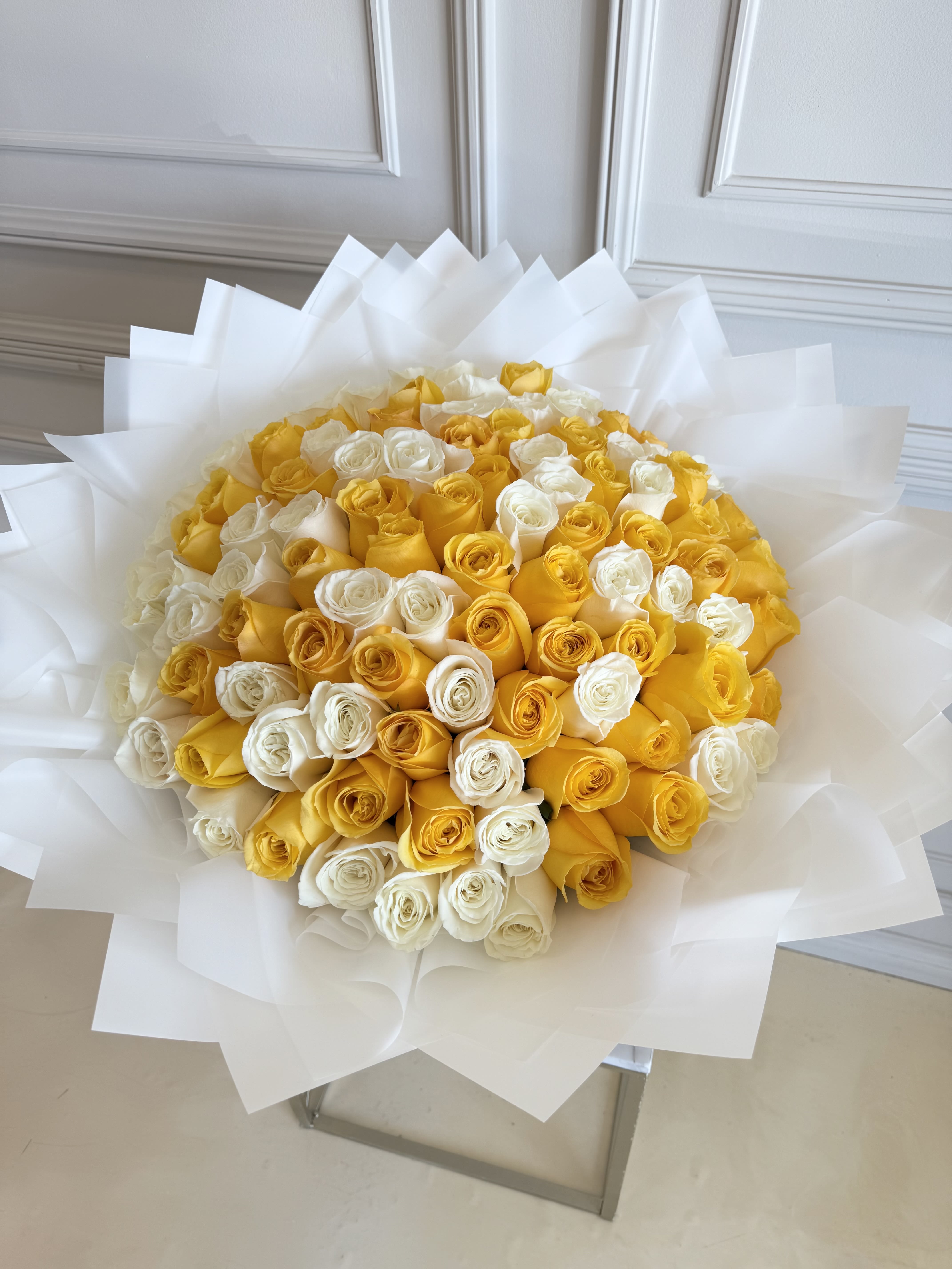 Bouquet of yellow and white roses wrapped in white paper