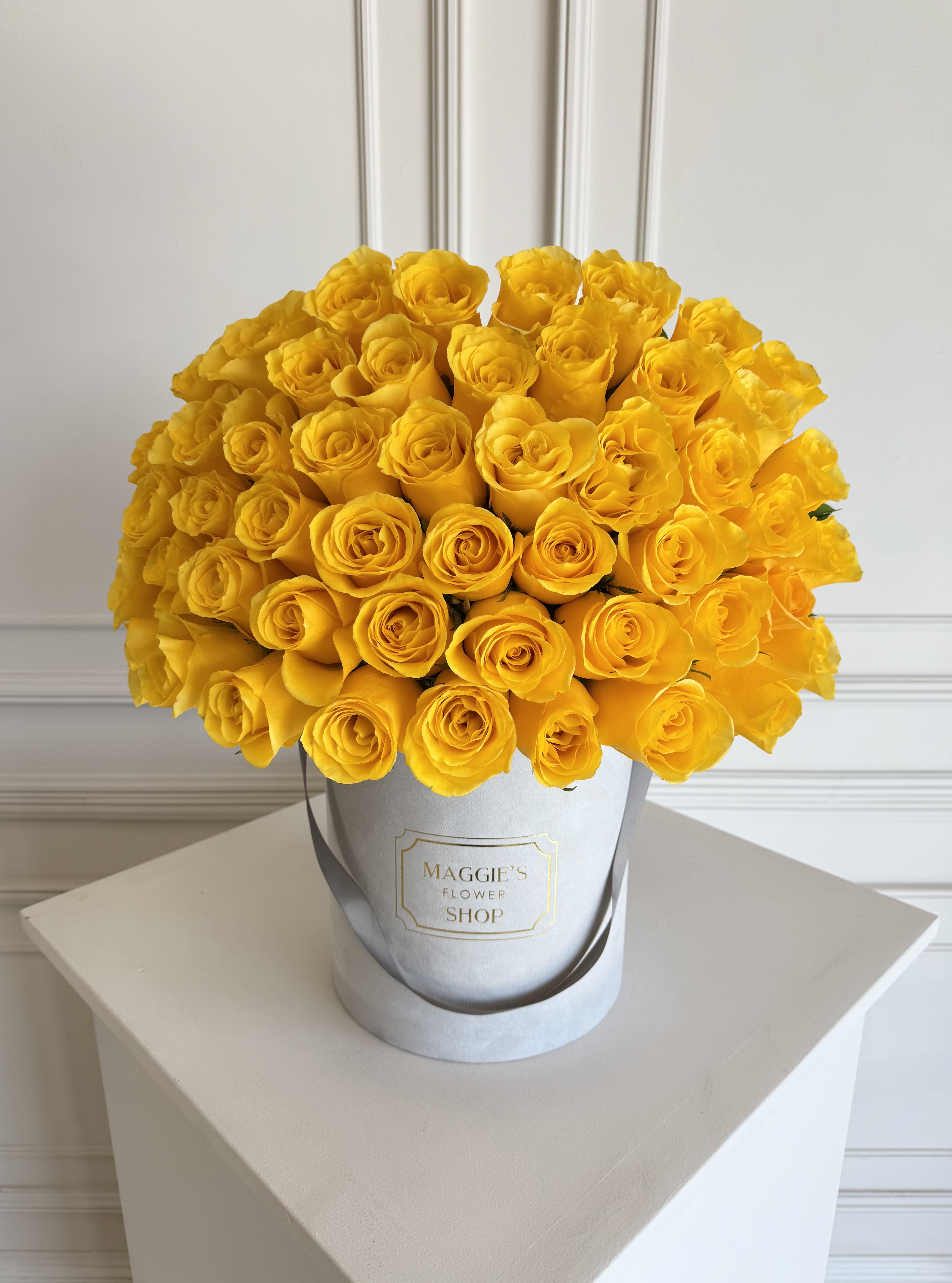 Bouquet of bright yellow roses in a silver hat box