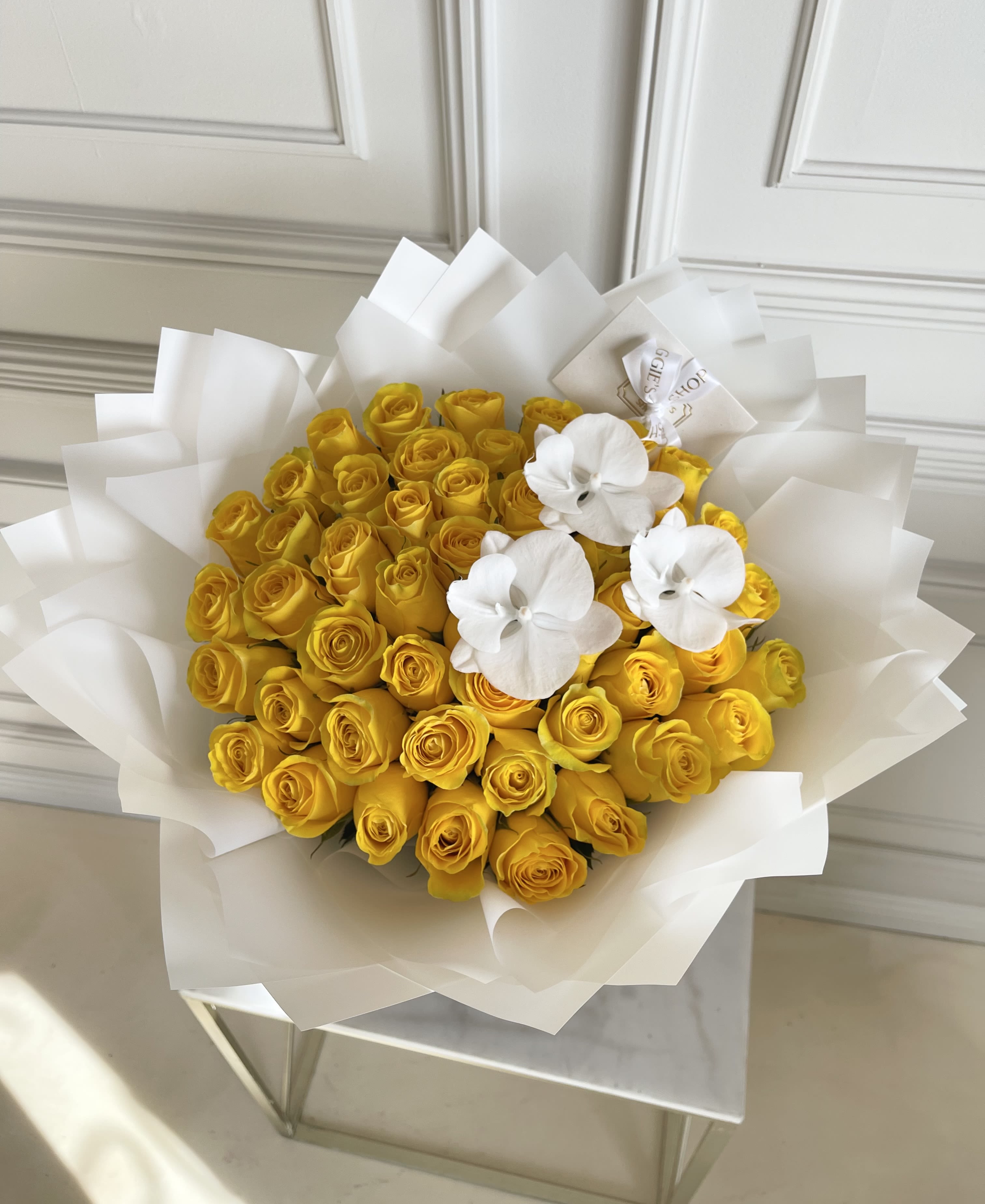 Bouquet of yellow roses with white orchids wrapped in white paper