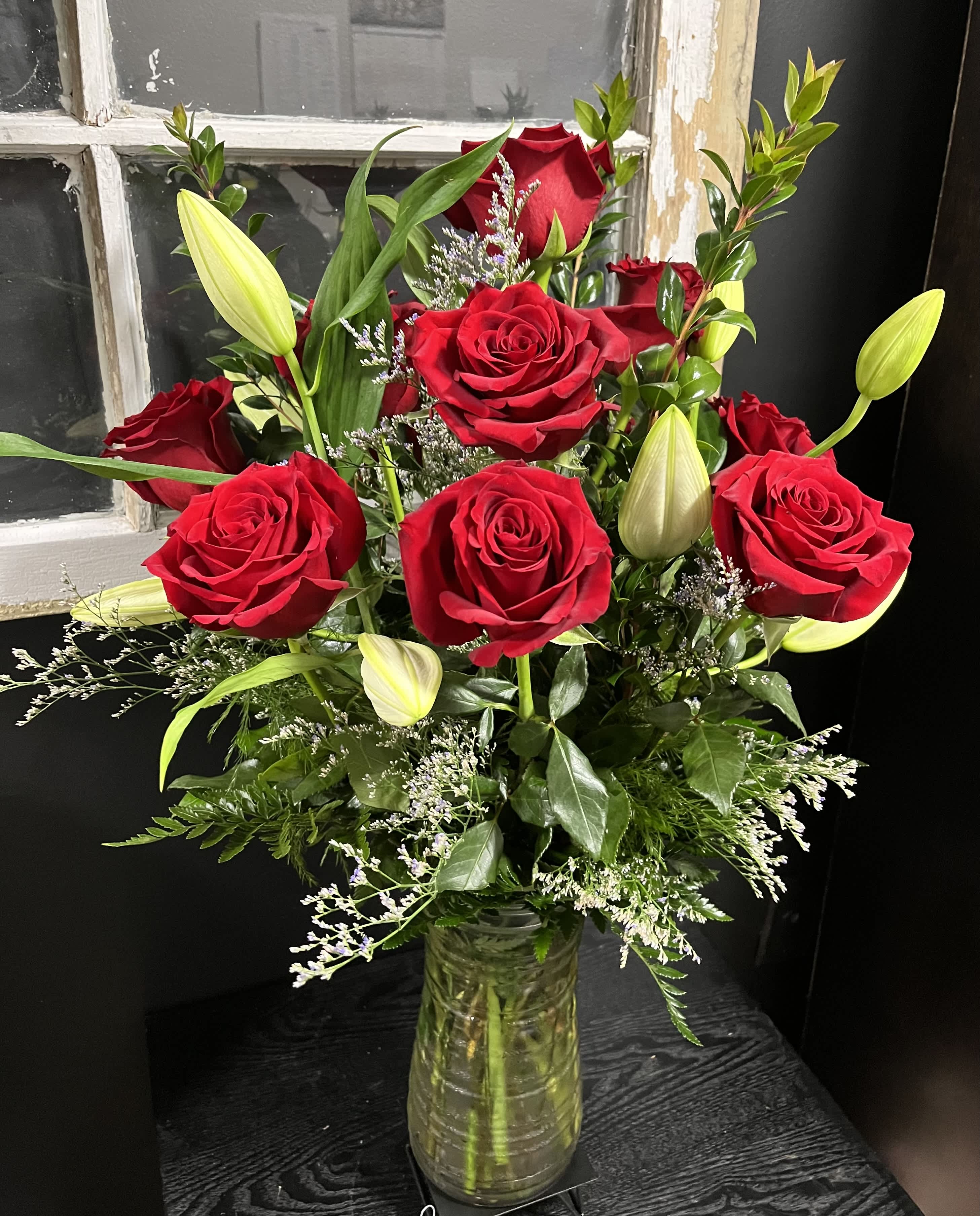 Red roses and lily buds in a clear glass vase