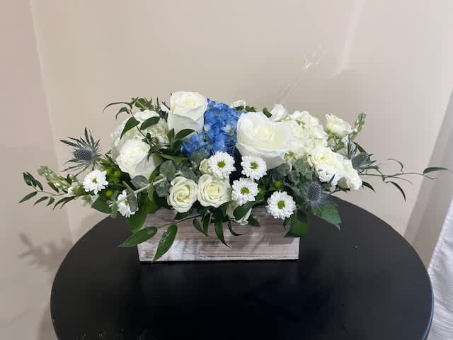 Low white and blue flower arrangement with roses and hydrangea in a rectangular wooden box