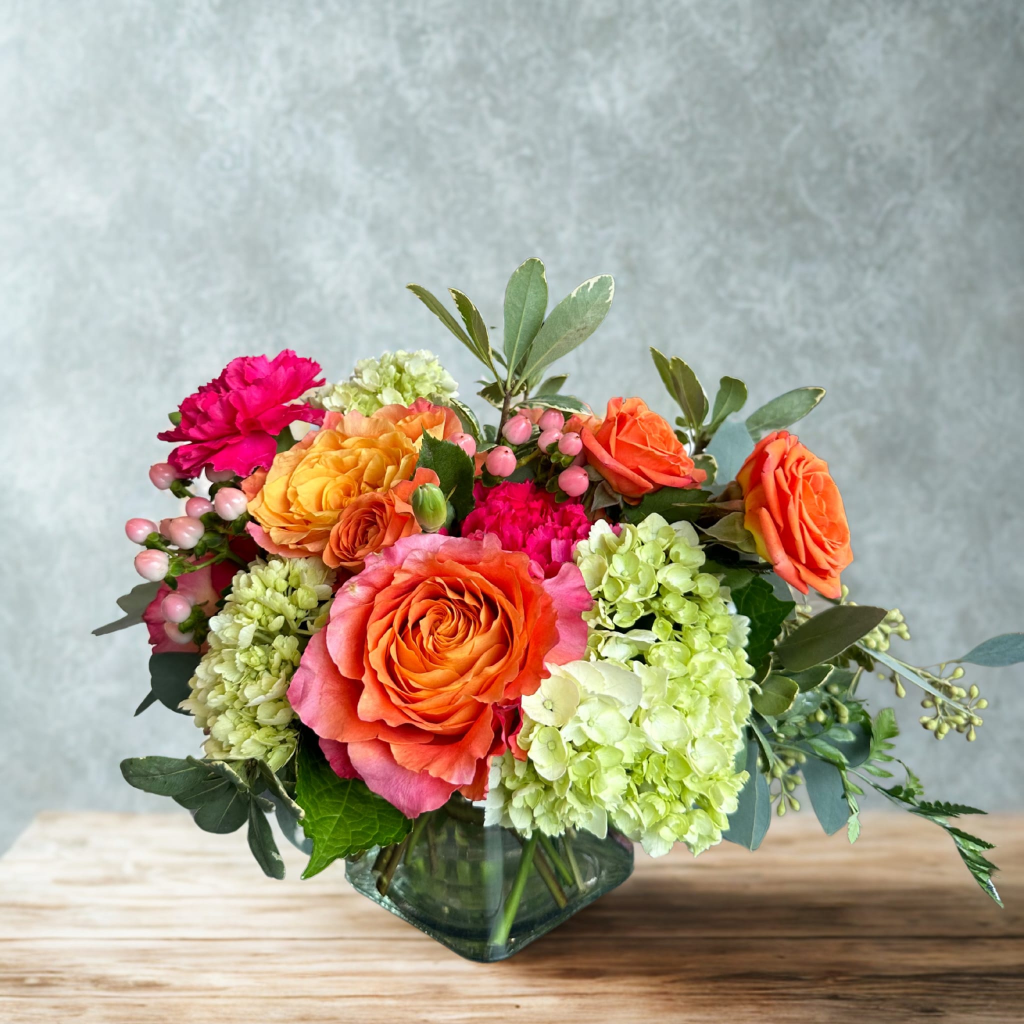 Orange roses and green hydrangeas in a glass vase