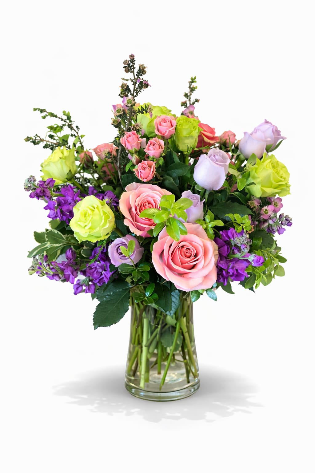 Mixed roses and purple flowers arranged in a clear glass vase