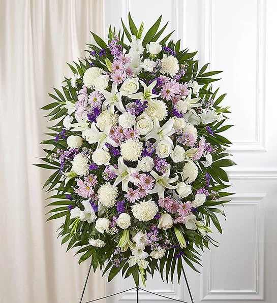 Large white and lavender funeral spray on an easel