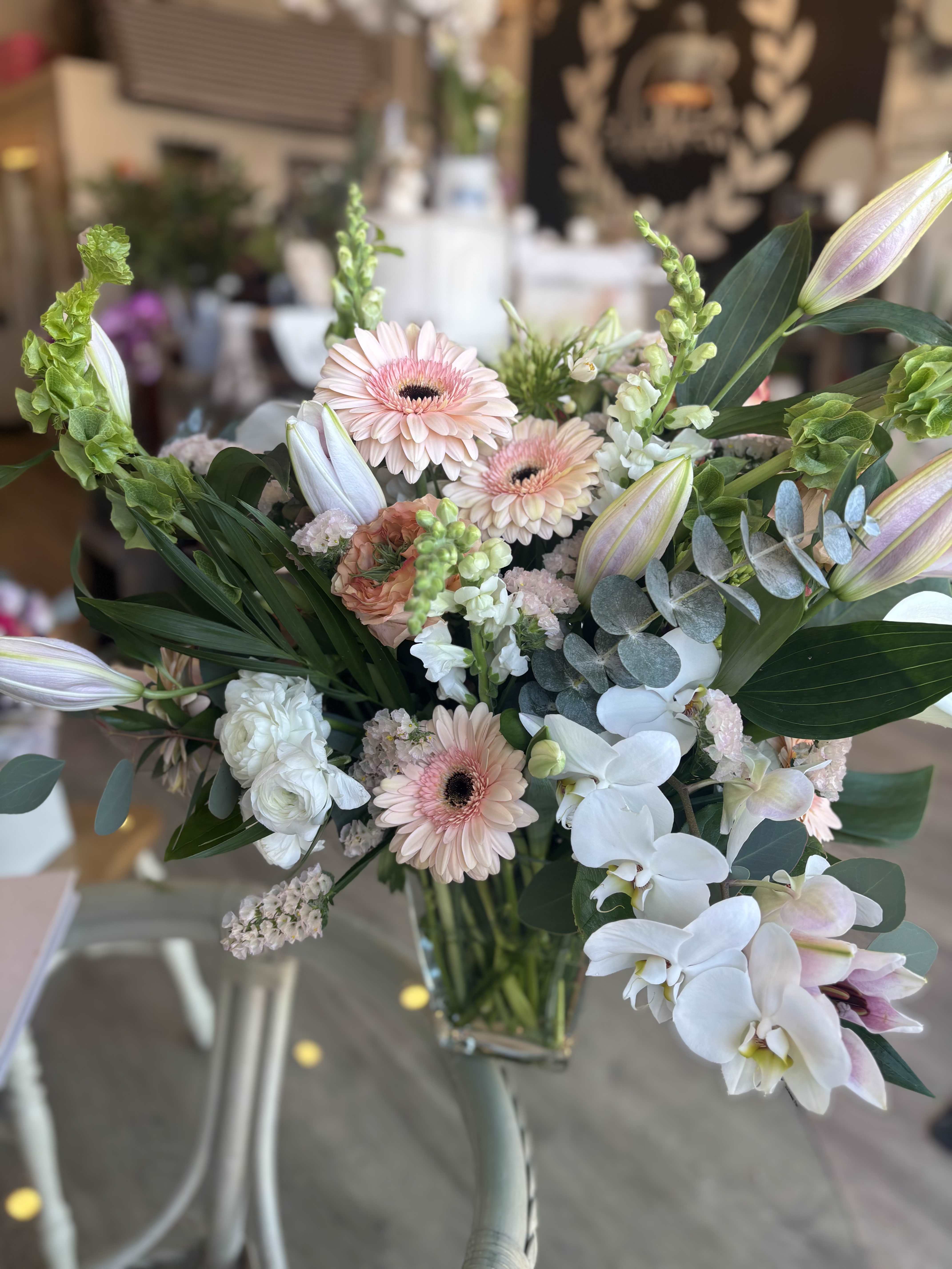Mixed bouquet with pale pink gerbera daisies and white orchids in a glass vase