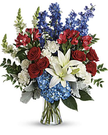 Red roses, white lilies, and blue flowers in a glass vase