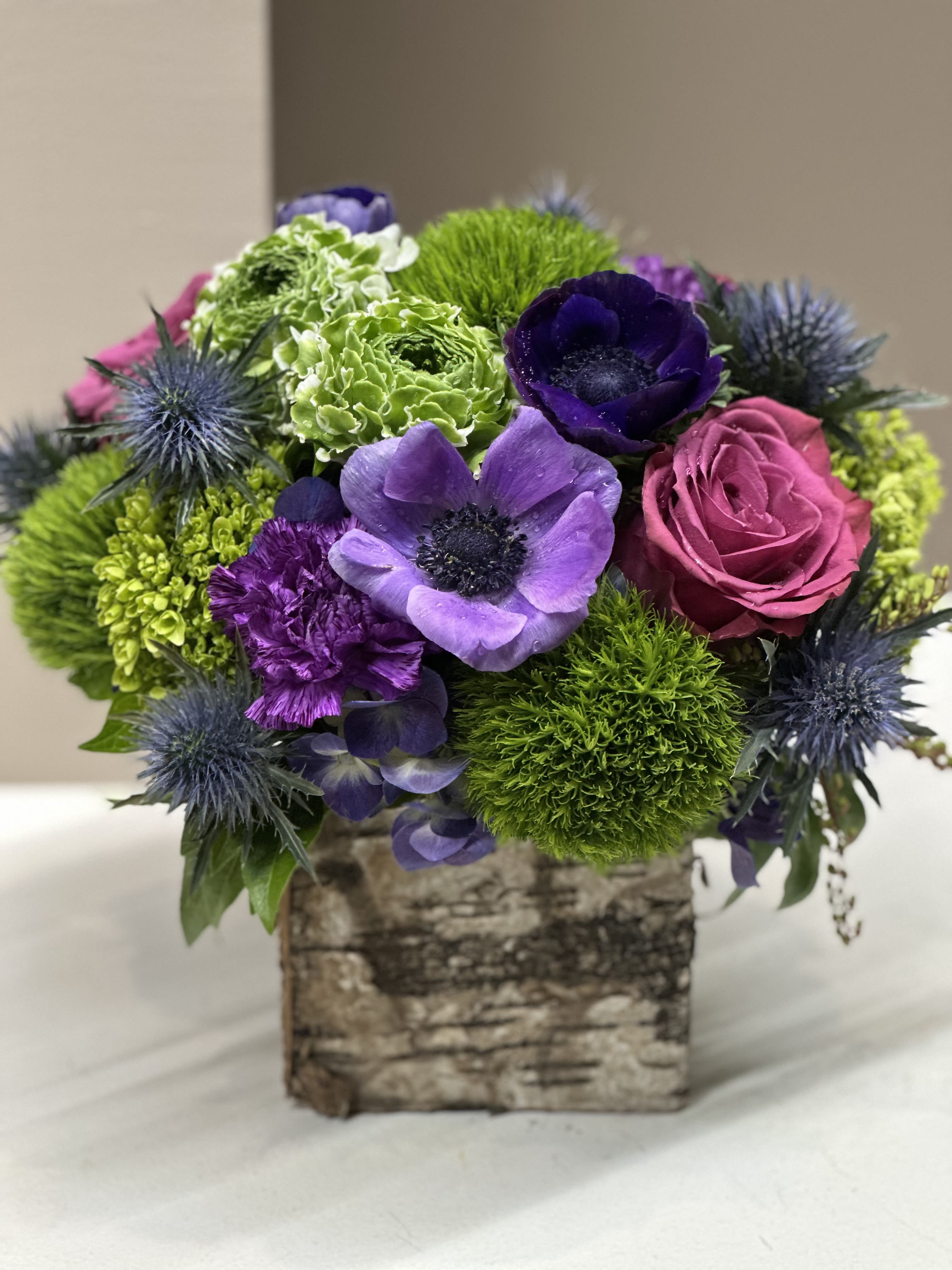Bouquet of purple, pink, and green flowers in a birch-style box