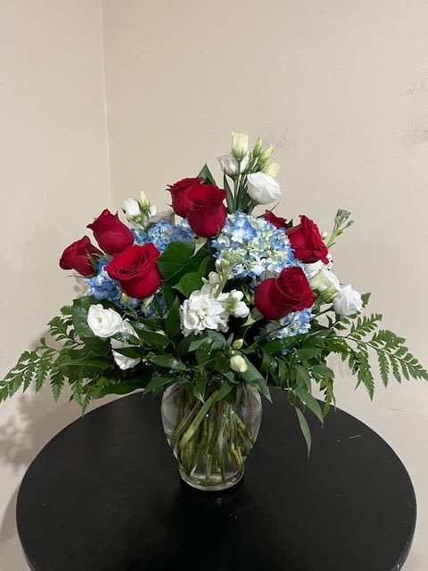 Red roses and blue hydrangeas in a clear glass vase