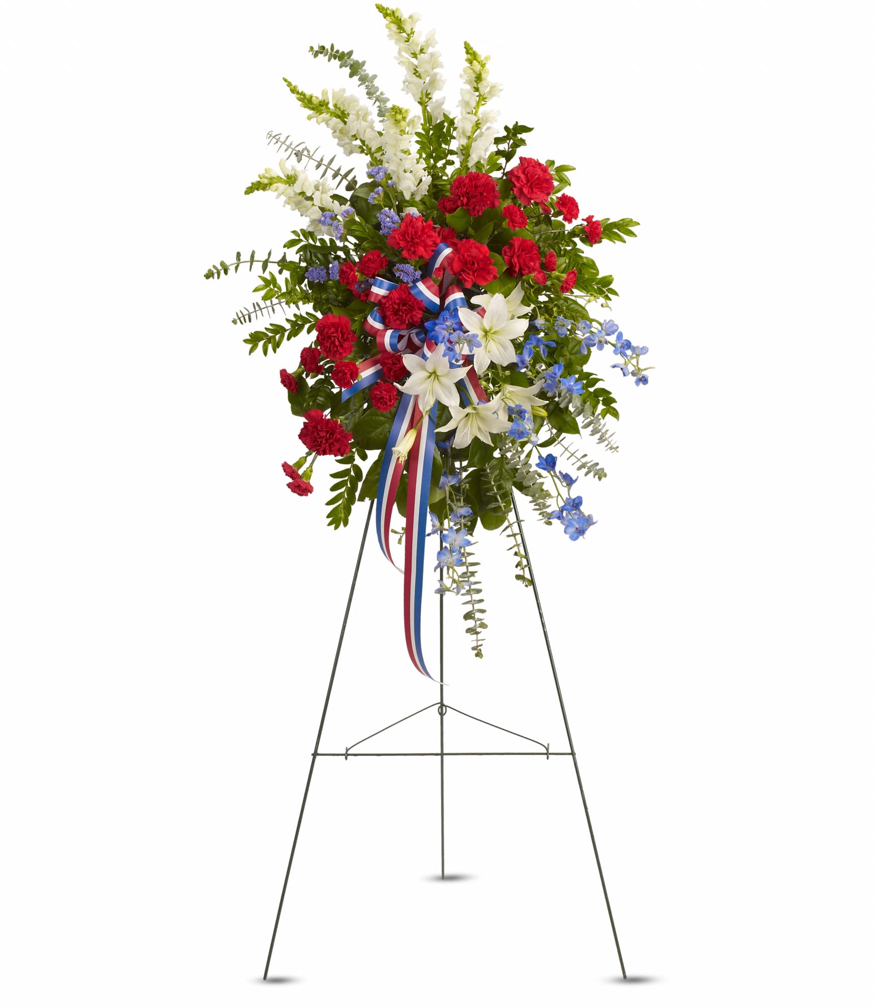 Standing floral spray with red carnations, white lilies, and blue flowers on an easel
