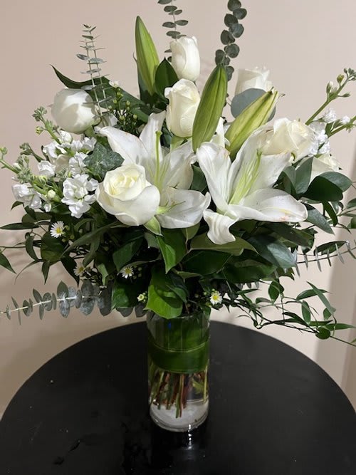 White lilies and roses arranged in a glass vase