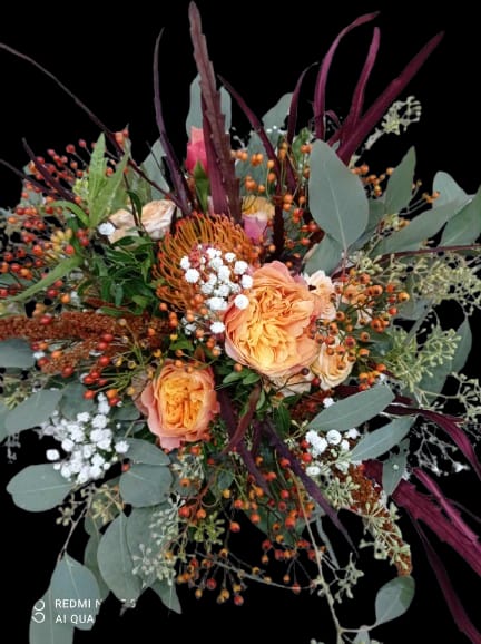 Wild Autumn  - Peach roses clustered at the heart of this loose, garden-style flower arrangement give it a warm, autumnal glow-perfect as a birthday bouquet, a thank-you gift, or a seasonal fall surprise for someone who loves textured, natural designs. The asymmetrical silhouette and dramatic height from long burgundy and gray-green foliage make the recipient feel genuinely seen, as if these stems were freshly gathered from a late-summer patch just for them.  This mixed bouquet pairs soft peach and pink roses with a standout orange pincushion bloom for unexpected texture, plus small white filler blooms and abundant orange berry sprays woven throughout. The layered mix of colors-orange, pink, white, and purple-creates depth, while the varied foliage adds contrast and movement. Sized to read as an everyday yet special arrangement, it arrives ready to display; light trimming of stems and fresh water will keep the bouquet looking its best for days.