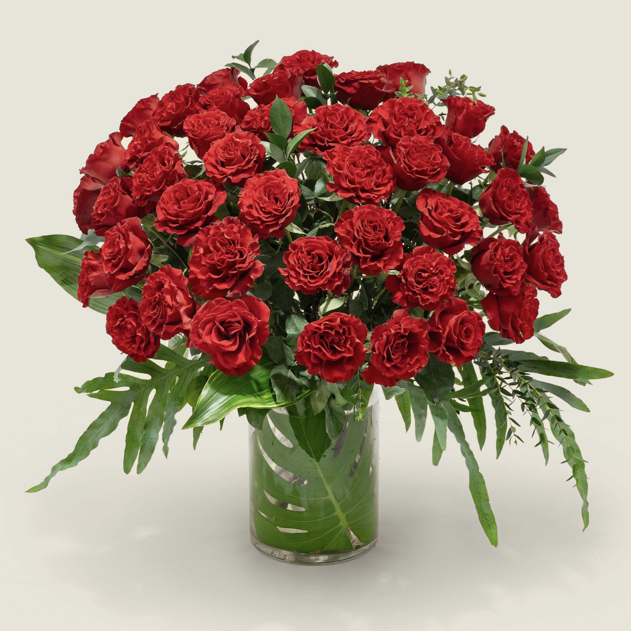 A large bouquet of red roses in a clear glass vase