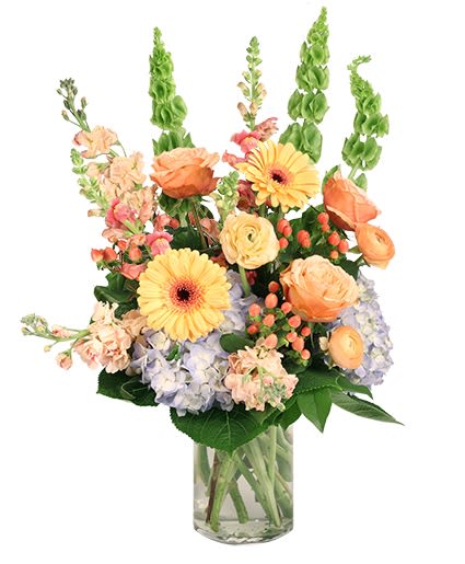 Mixed bouquet of peach and yellow flowers in a clear glass vase