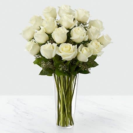 Tall clear vase of long-stem white roses arranged in a rounded cluster