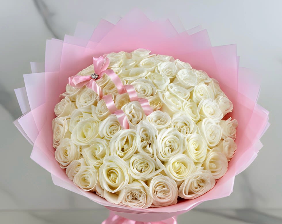 Bouquet of cream roses wrapped in pink paper with a pink ribbon