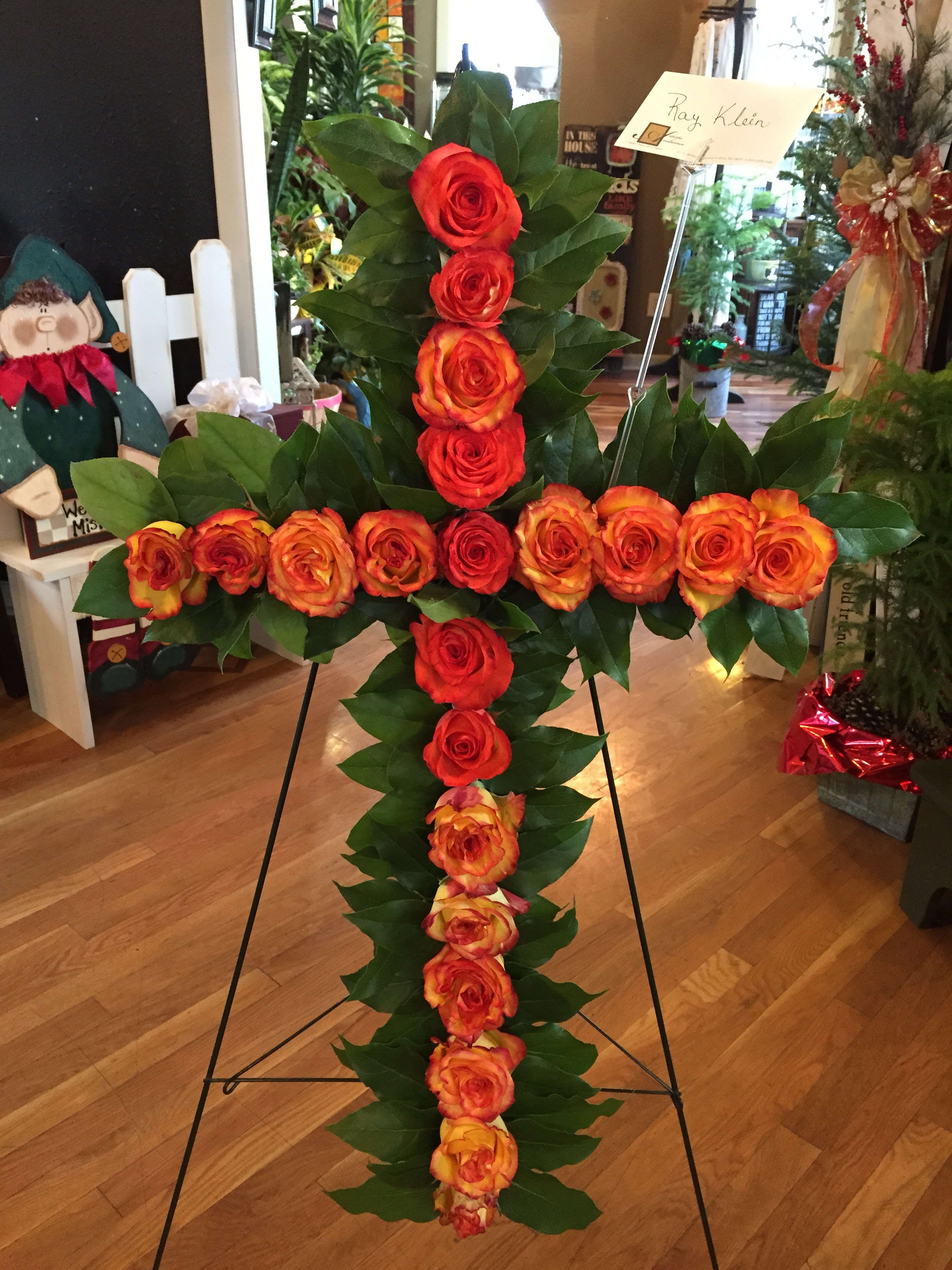 Cross-shaped rose arrangement on a stand with red and orange roses
