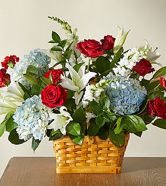 Basket arrangement of red roses, blue hydrangeas, and white lilies