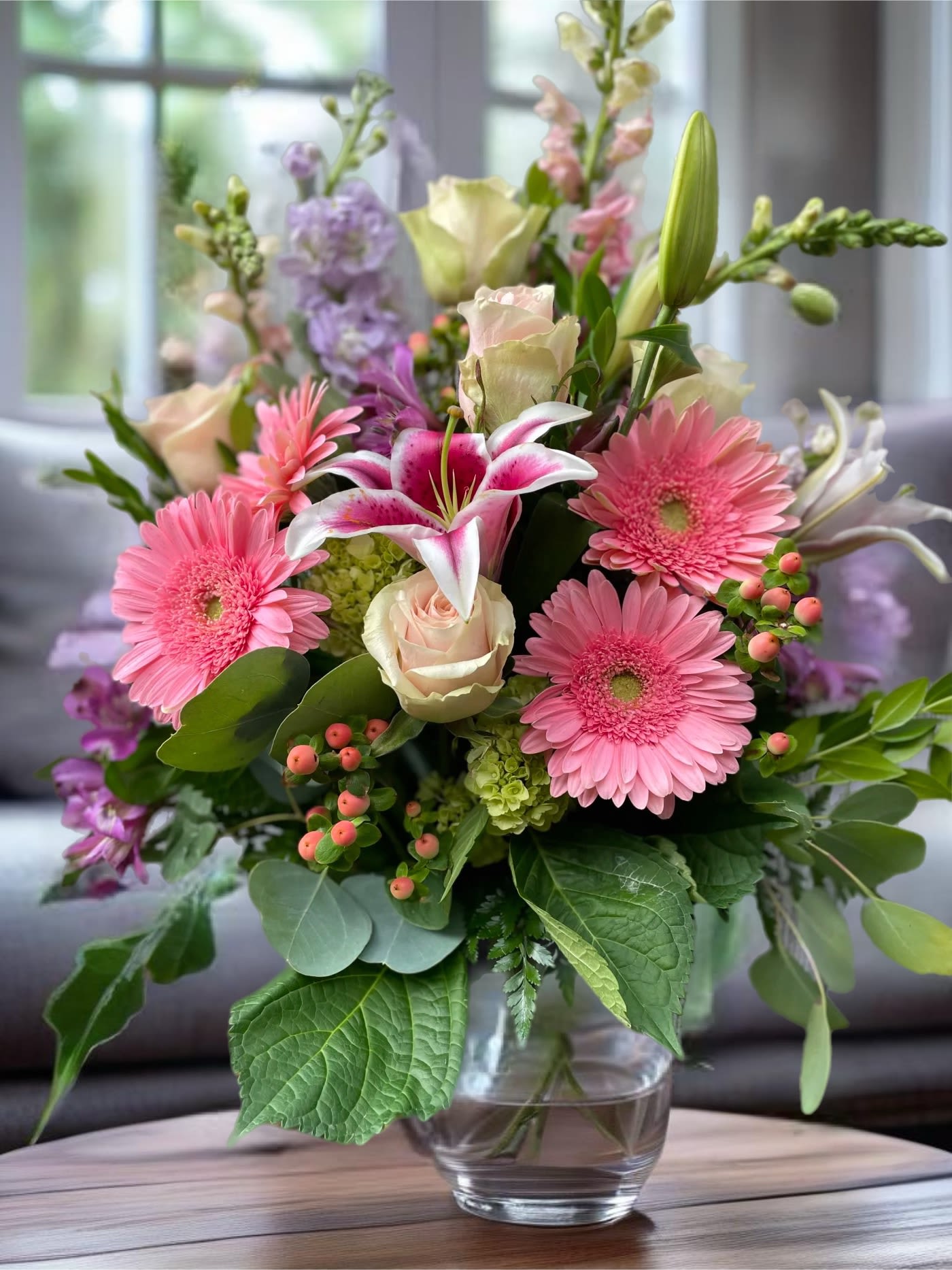 Pink gerbera daisies, lilies, and roses in a glass vase