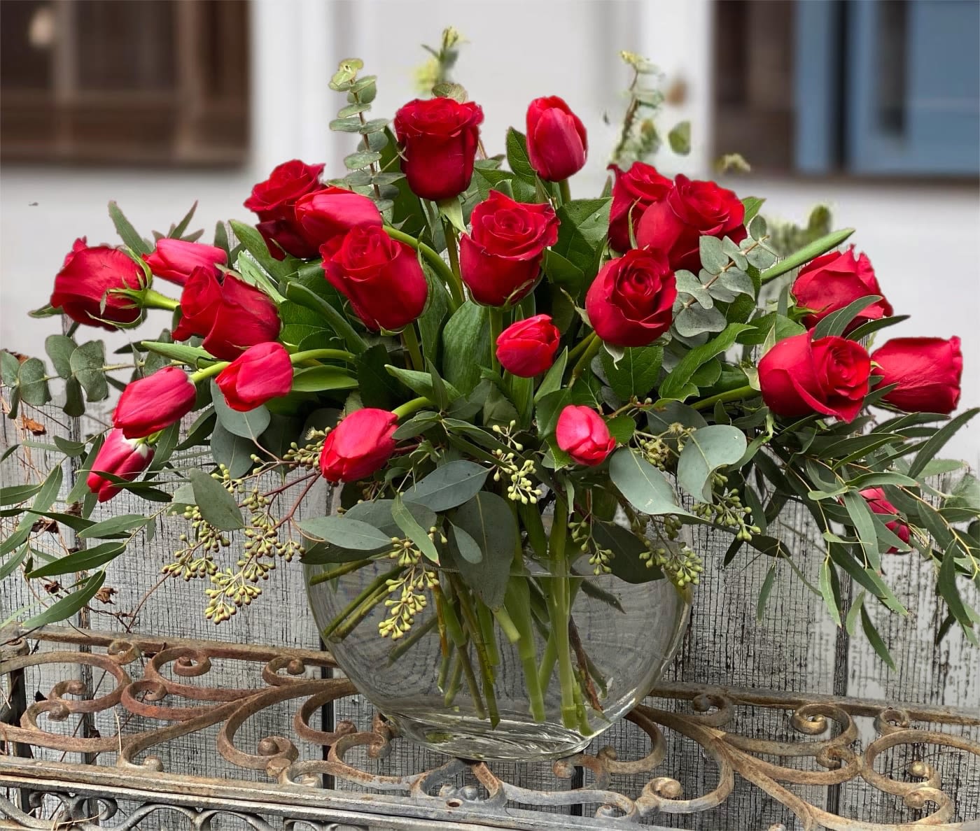 Red roses arranged in a clear glass vase with eucalyptus