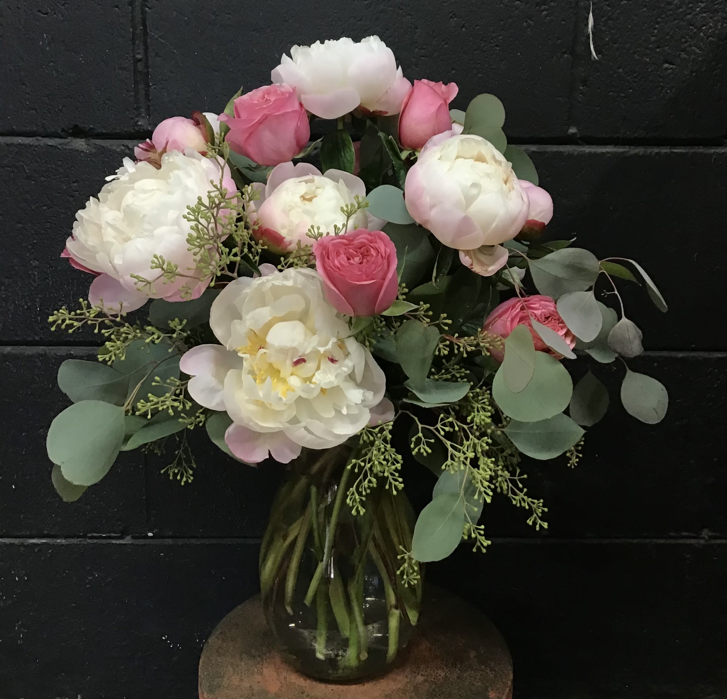 Pink and white peonies and roses in a glass vase